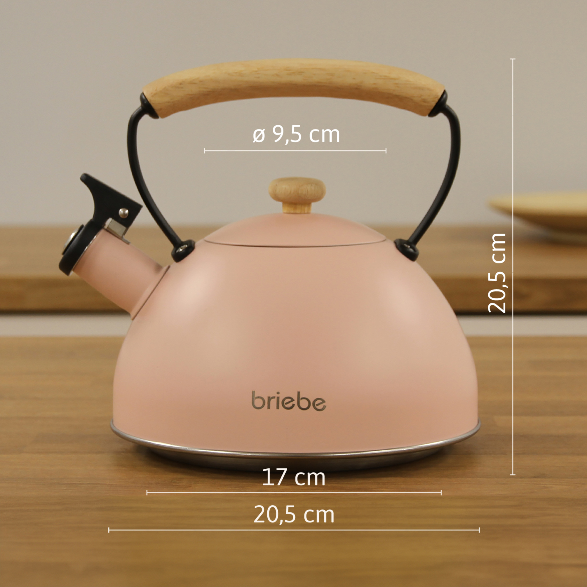 Una tetera rosa con asa de madera y un pequeño pomo de madera. Se proporcionan medidas, sobre una superficie de madera.