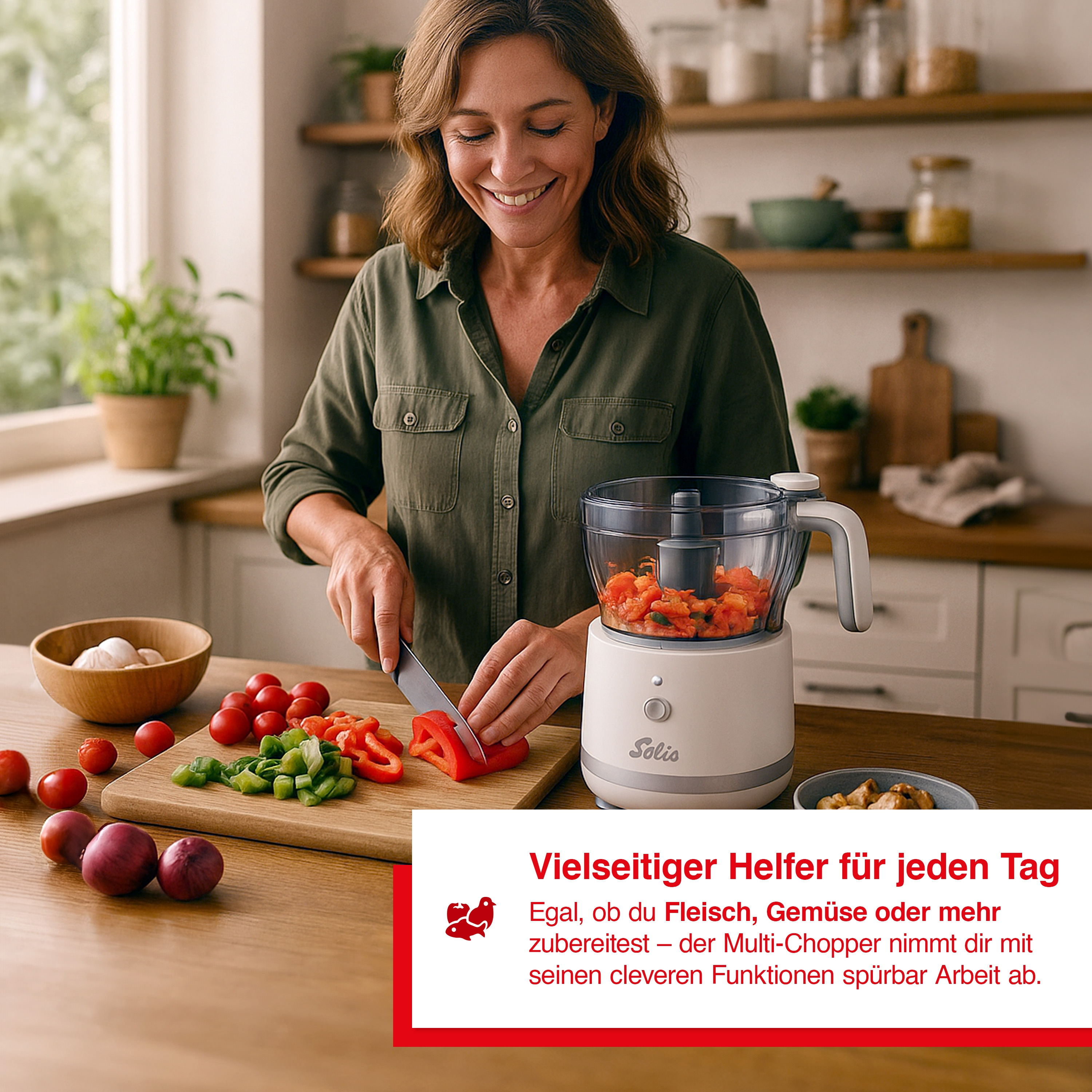Donna che taglia peperoni rossi vicino a un robot da cucina, pomodori, cipolle e verdure sul tavolo.
