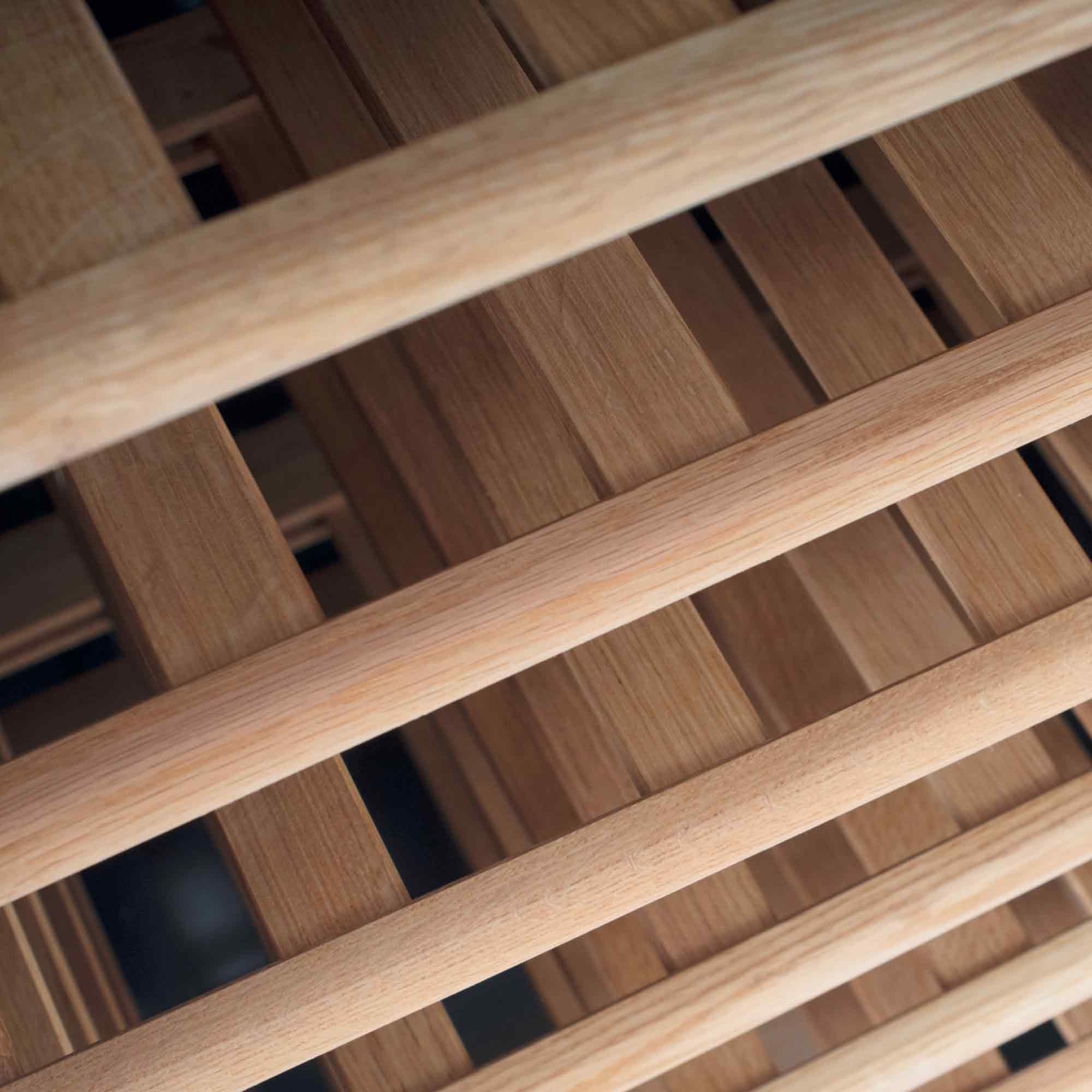 Nahaufnahme eines Weinregals aus Holz. Horizontale runde Stäbe und vertikale Holzlatten bilden ein Gitter.
