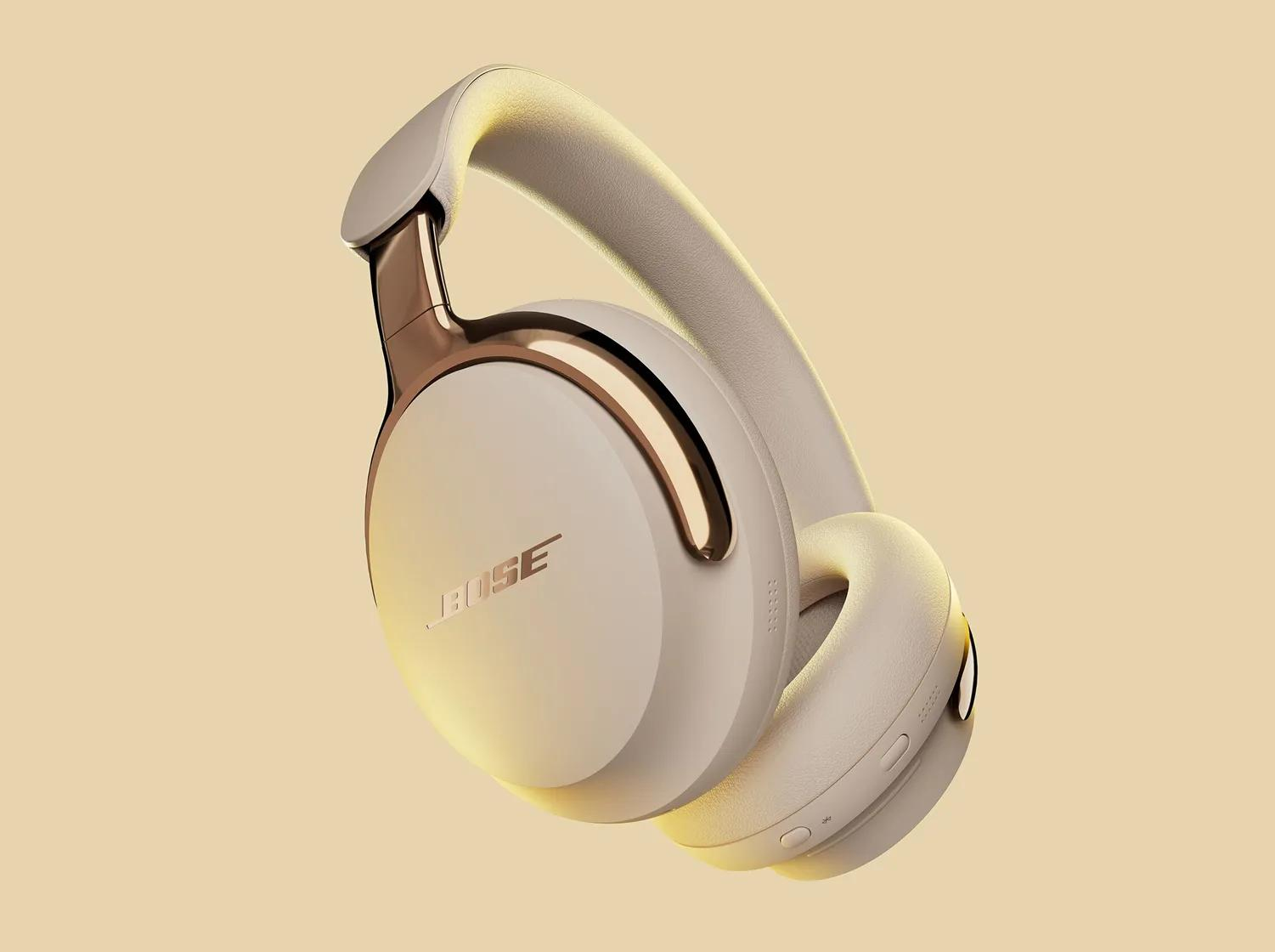 Cremefarbene Bose-Kopfhörer mit goldenen Akzenten auf weichem gelben Hintergrund. Das Design ist elegant und modern.