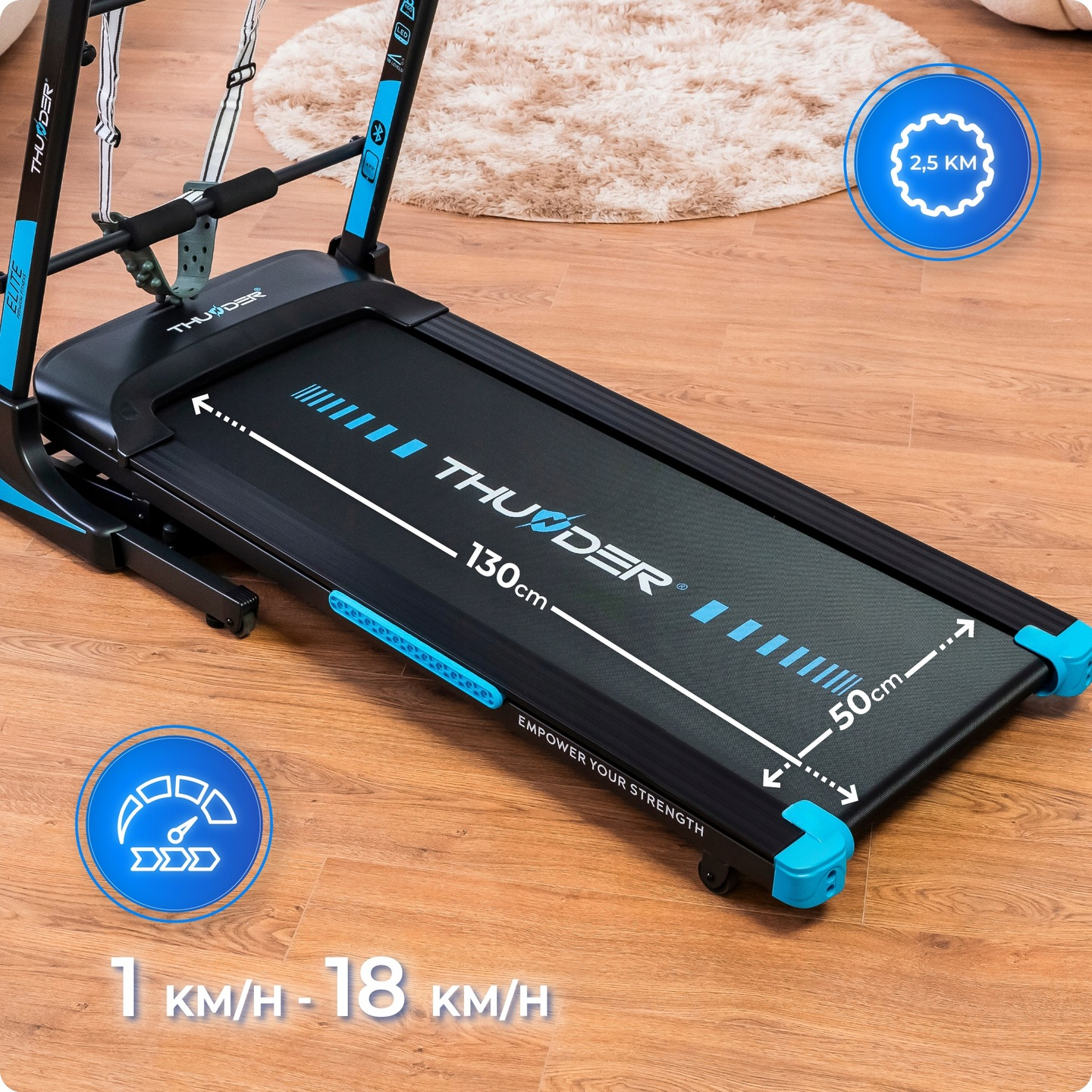 Bieżnia z niebieskimi akcentami, 130cm x 50cm, na drewnianej podłodze. Zakres prędkości 1-18 km/h. Dywan w tle.