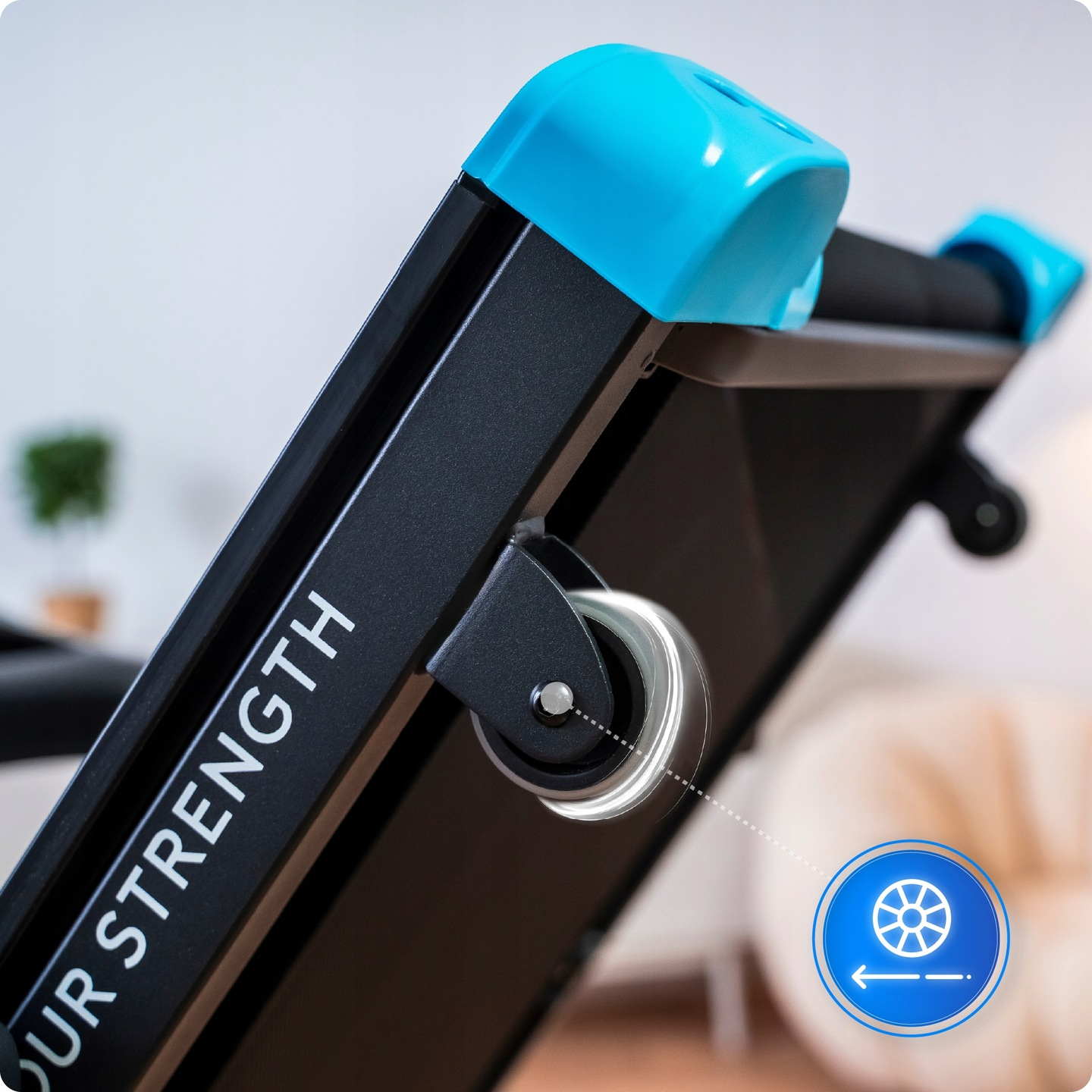 Zbliżenie bieżni. Czarna rama z niebieskimi akcentami. Widoczne koło. Tekst na ramie: "YOUR STRENGTH".