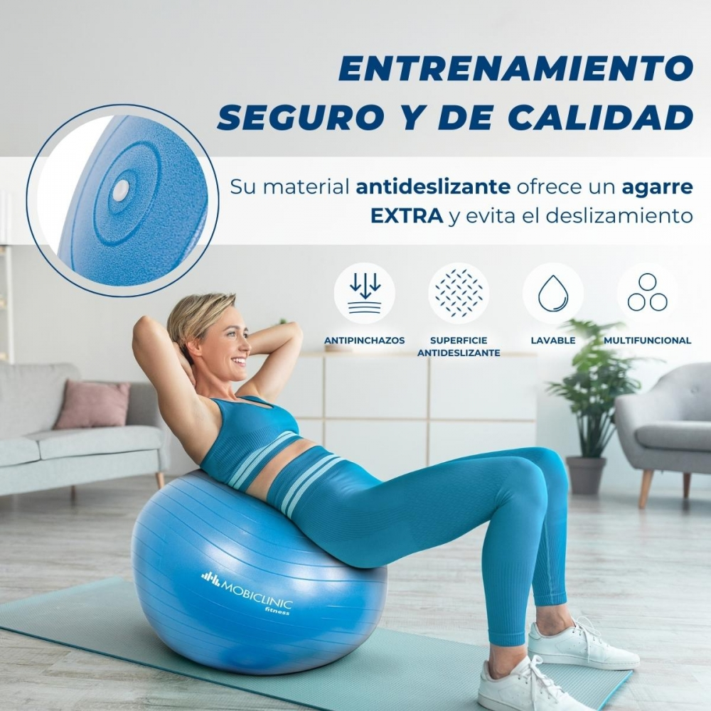 Mujer con ropa deportiva azul sobre una pelota de ejercicios azul. La pelota está sobre una esterilla. Texto superior: 'Entrenamiento seguro y de calidad.'