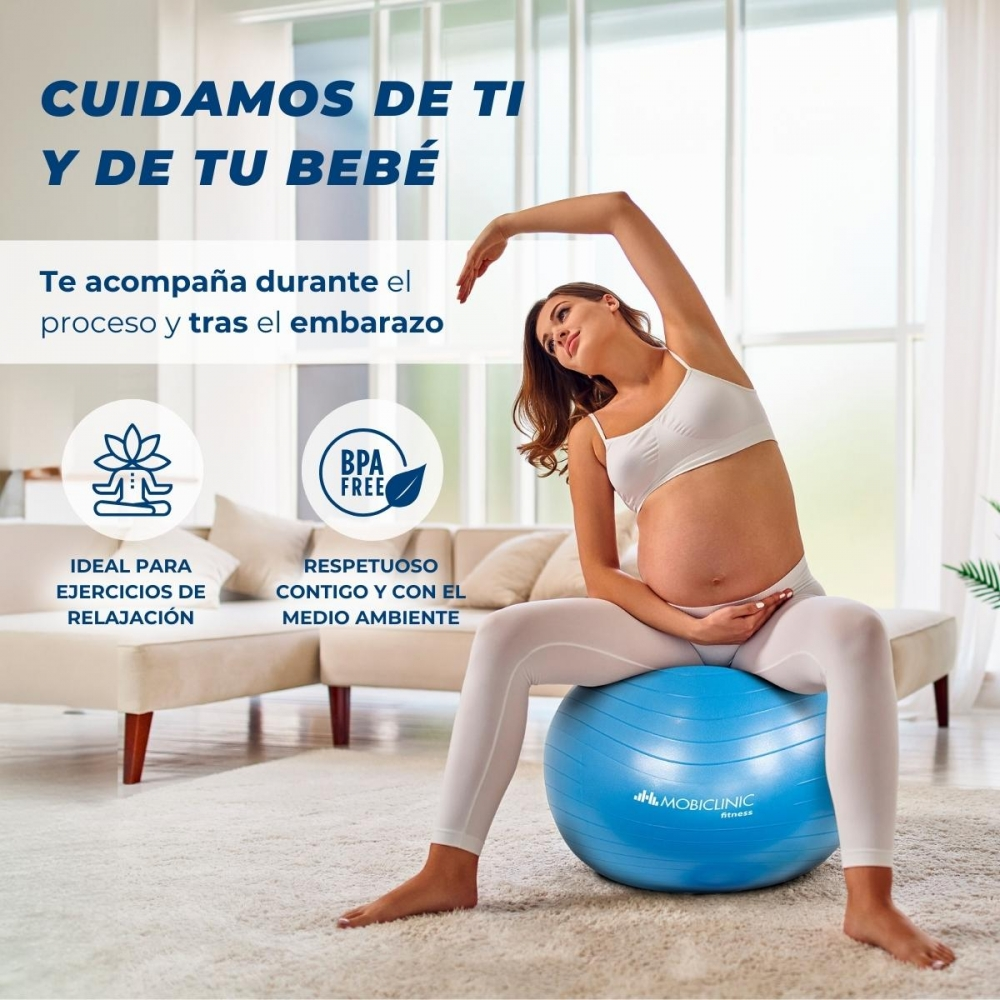 Mujer embarazada en ropa deportiva blanca sobre balón azul, estirando el brazo. Texto en español promociona el producto para el embarazo.