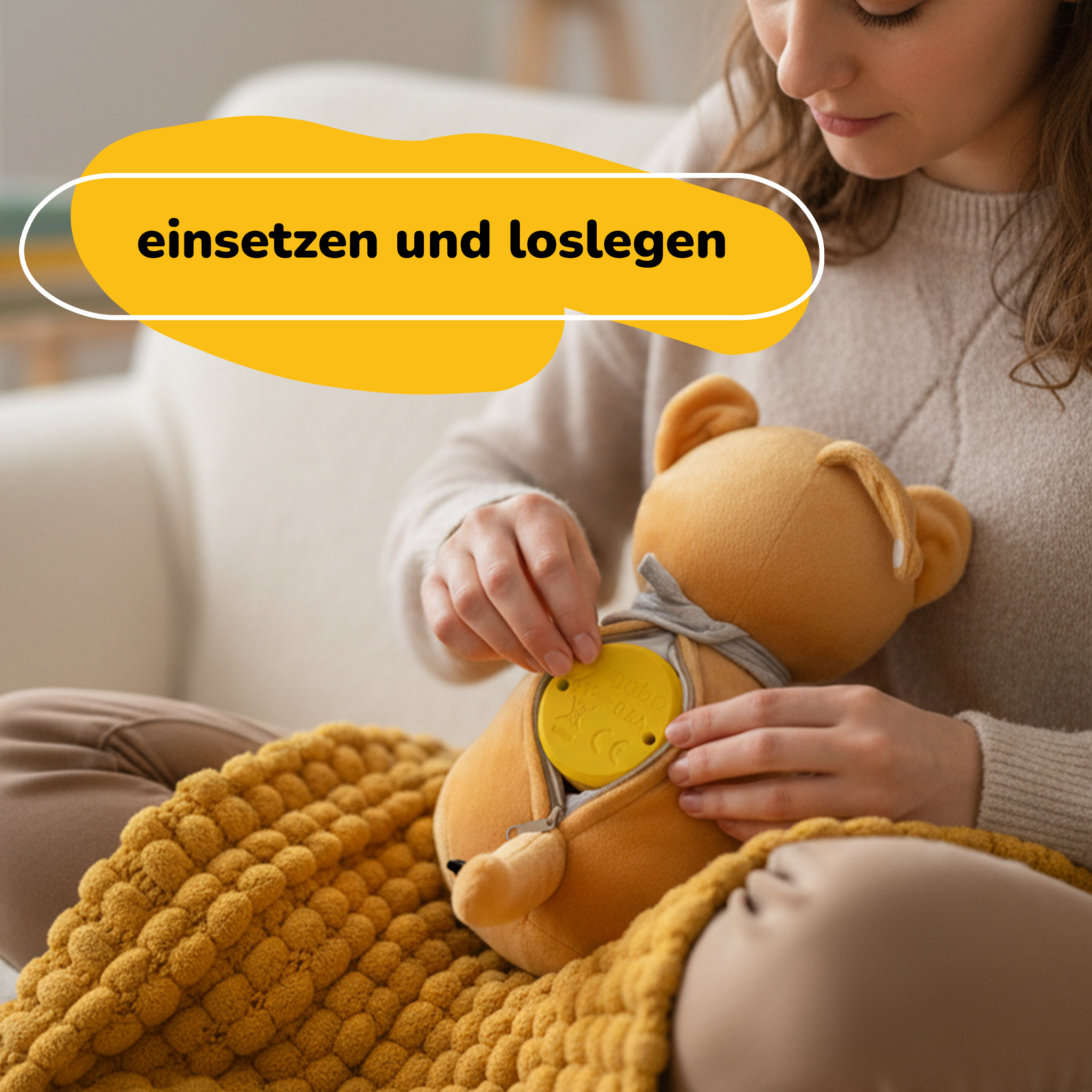 Eine Frau legt eine gelbe Scheibe in einen Teddybären. Auf ihrem Schoß liegt eine gelbe Decke. Text: einsetzen und loslegen.