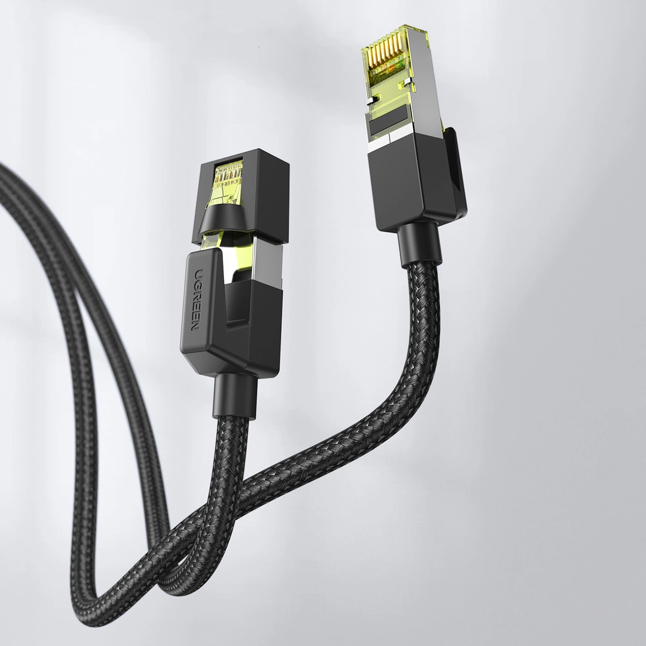 Dwa czarne kable ethernet z wtyczkami na białym tle. Jedna wtyczka ma etykietę UGREEN.