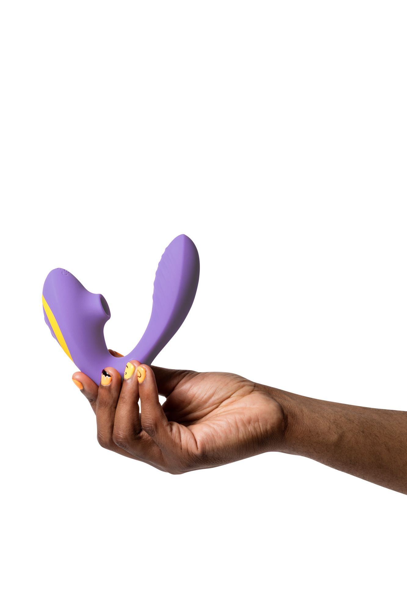 Una mano sostiene un juguete sexual morado con detalles amarillos. La persona tiene esmalte de uñas naranja y fondo blanco.