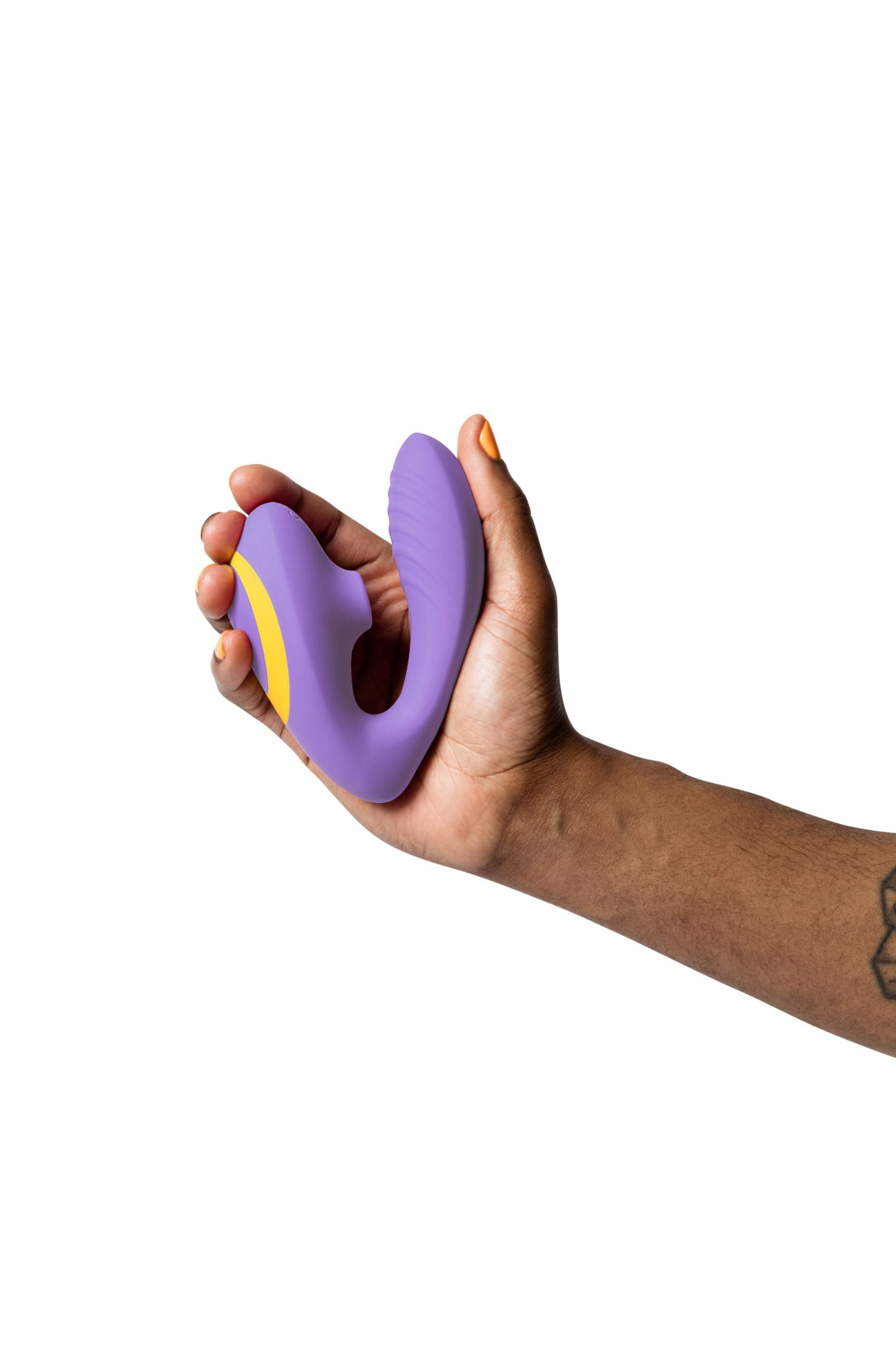 Una mano sostiene un juguete sexual morado con acentos amarillos. La persona tiene piel oscura y esmalte de uñas naranja.