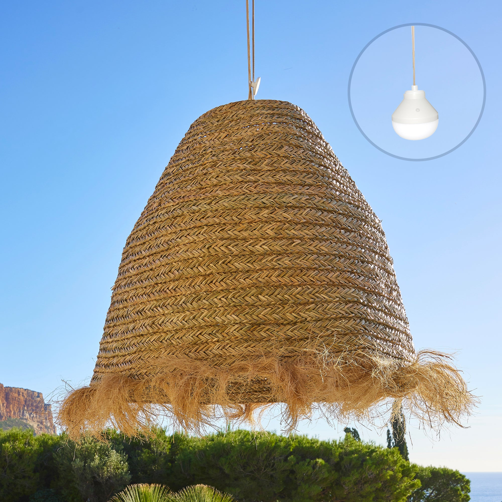 Ein gewebter Strohschirm hängt vor blauem Himmel. Eine weiße Lampe wird in einem Kreis gezeigt.