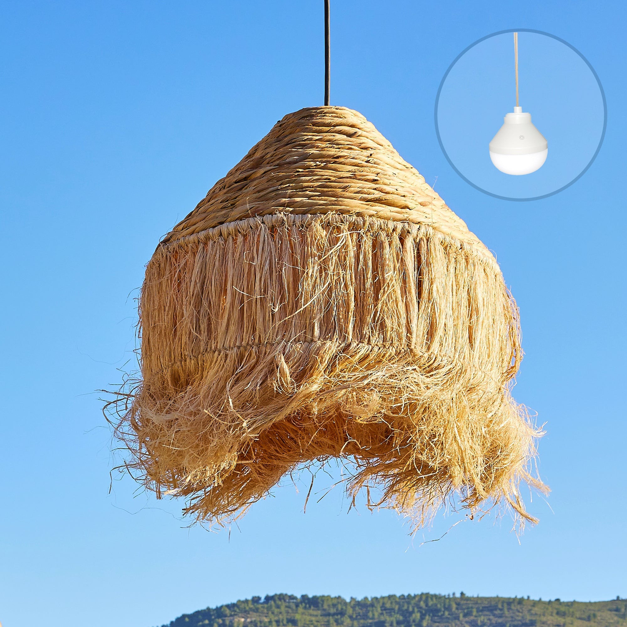 Ein gewebter Strohschirm hängt vor blauem Himmel. Ein kleiner Einsatz zeigt eine weiße Lampe.