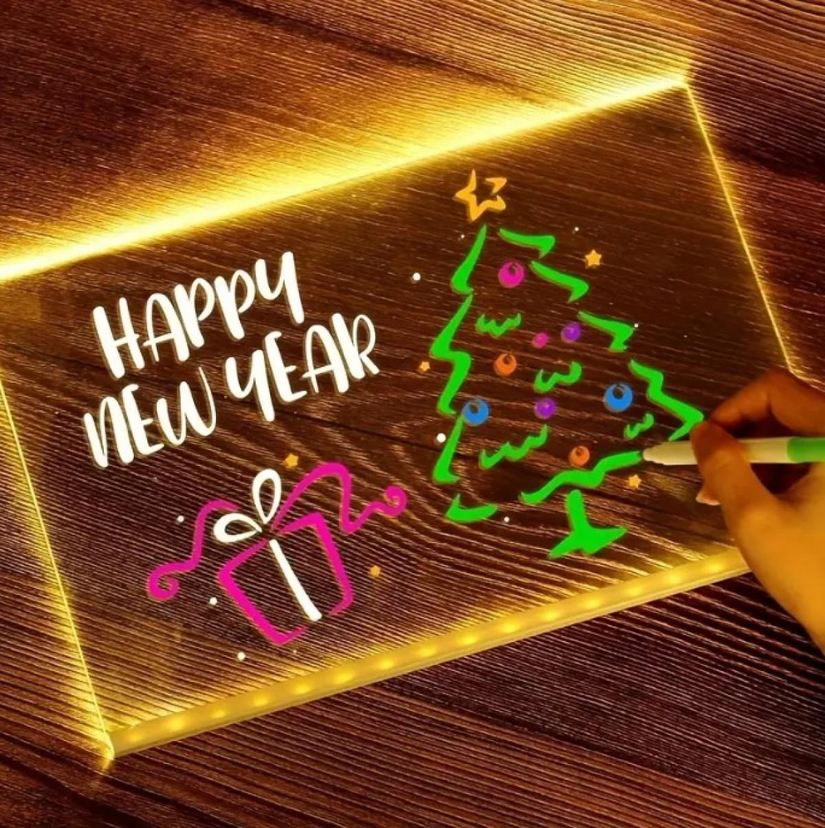 Ein leuchtendes Schild mit 'Happy New Year', einem Weihnachtsbaum und einem Geschenk wird gezeichnet. Eine Hand hält einen grünen Stift.