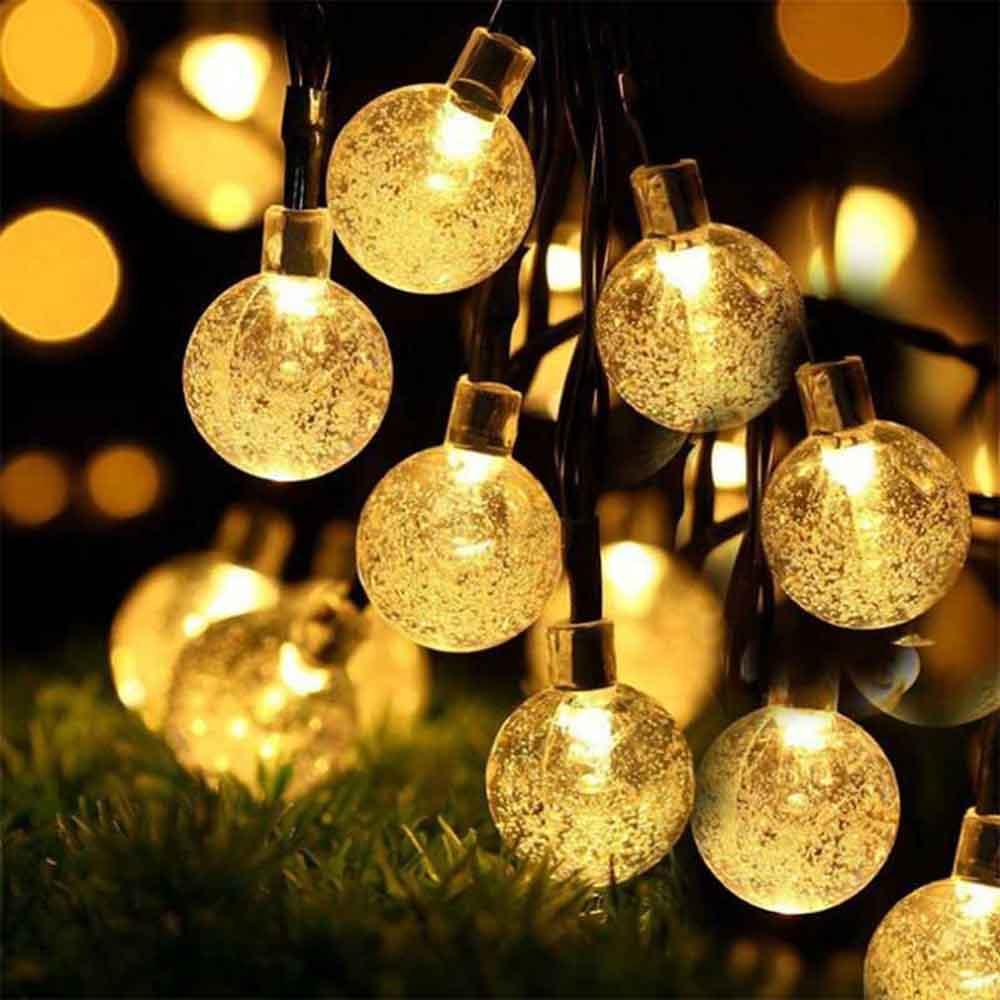 Lichterkette mit leuchtenden, runden Lichtern. Jede Glühbirne ist eine klare Kugel mit warmem gelben Schein, vor verschwommenem Hintergrund.