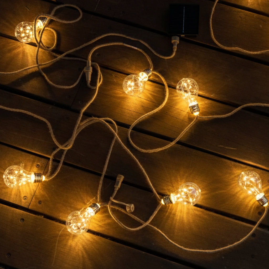 Lichterketten mit glühenden Glühbirnen. Die Glühbirnen liegen auf einer Holzoberfläche. Die Lichter sind solarbetrieben.