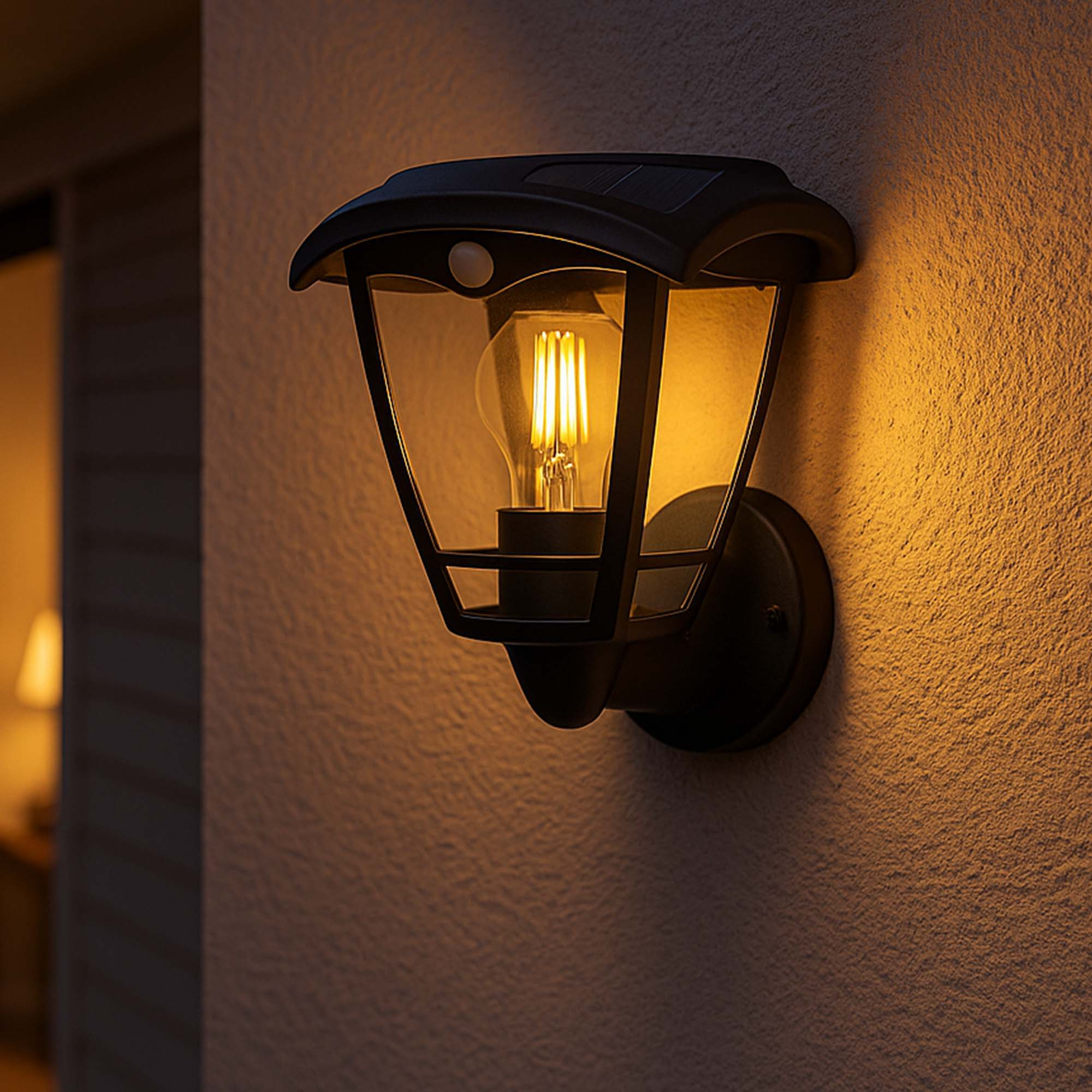 Schwarze Außenlampe mit leuchtender Glühbirne an strukturierter Wand. Der Hintergrund ist schwach beleuchtet.