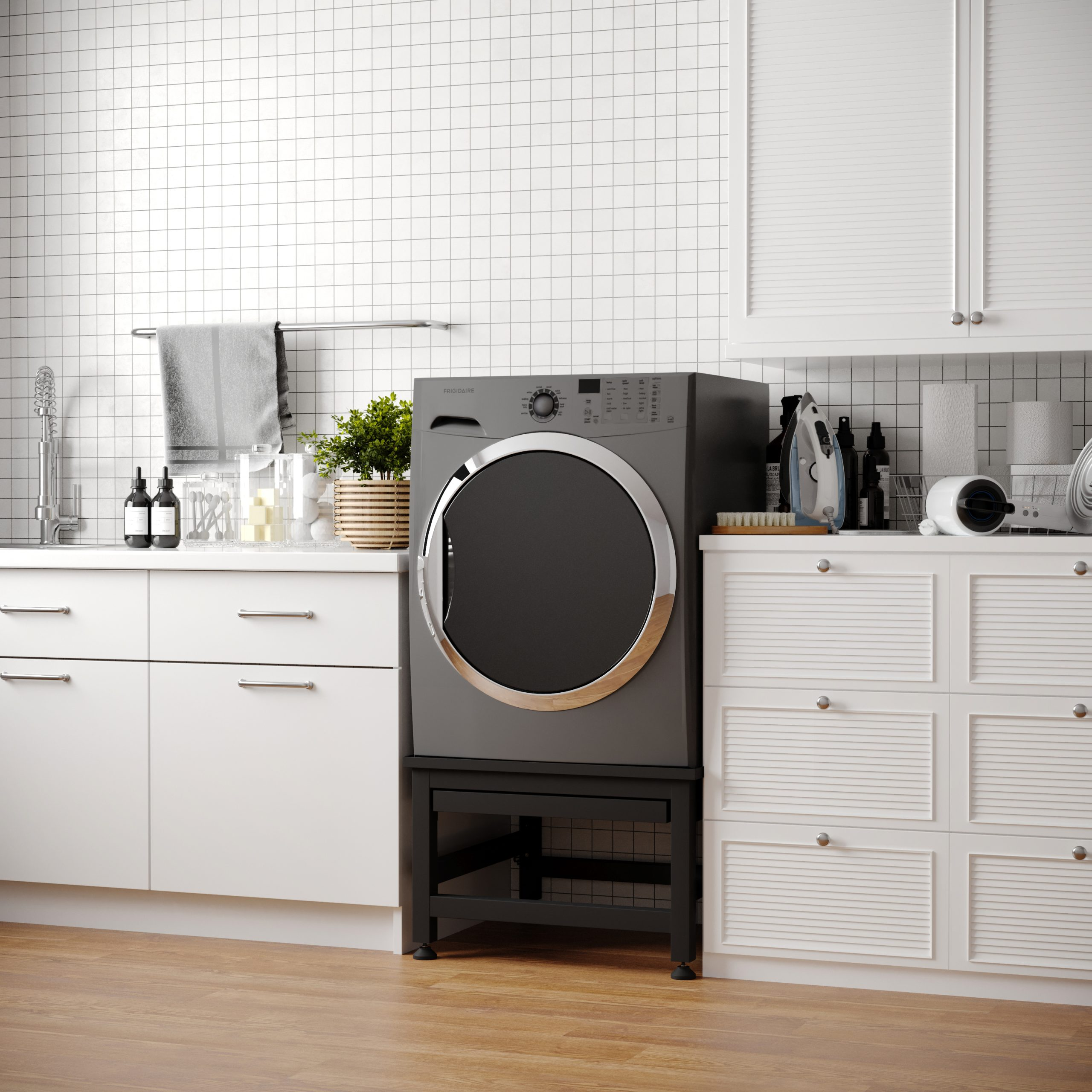 Wasruimte met een grijze wasmachine, witte kasten en een houten vloer. Een handdoek hangt aan een rek.