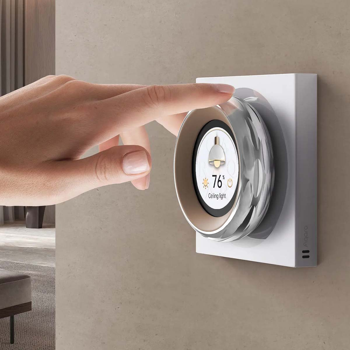 Ręka dotyka inteligentnego termostatu. Termostat wyświetla 76% i ikonę światła sufitowego. Urządzenie jest zamontowane na ścianie.