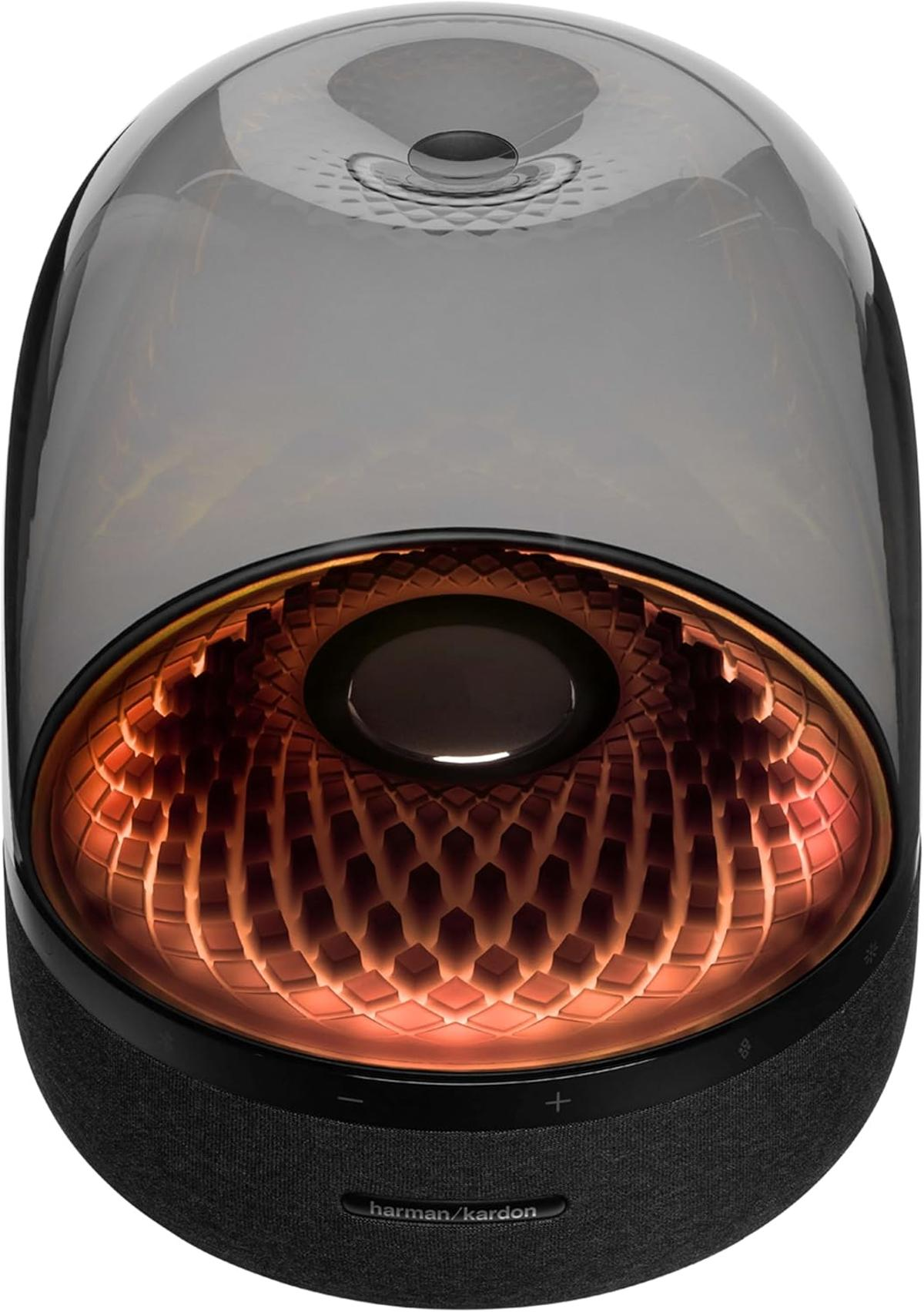 Ein moderner Lautsprecher mit transparenter Kuppel. Innen ein orangefarbenes Muster. Die Basis ist schwarz mit Bedienelementen und dem Harman Kardon Logo.