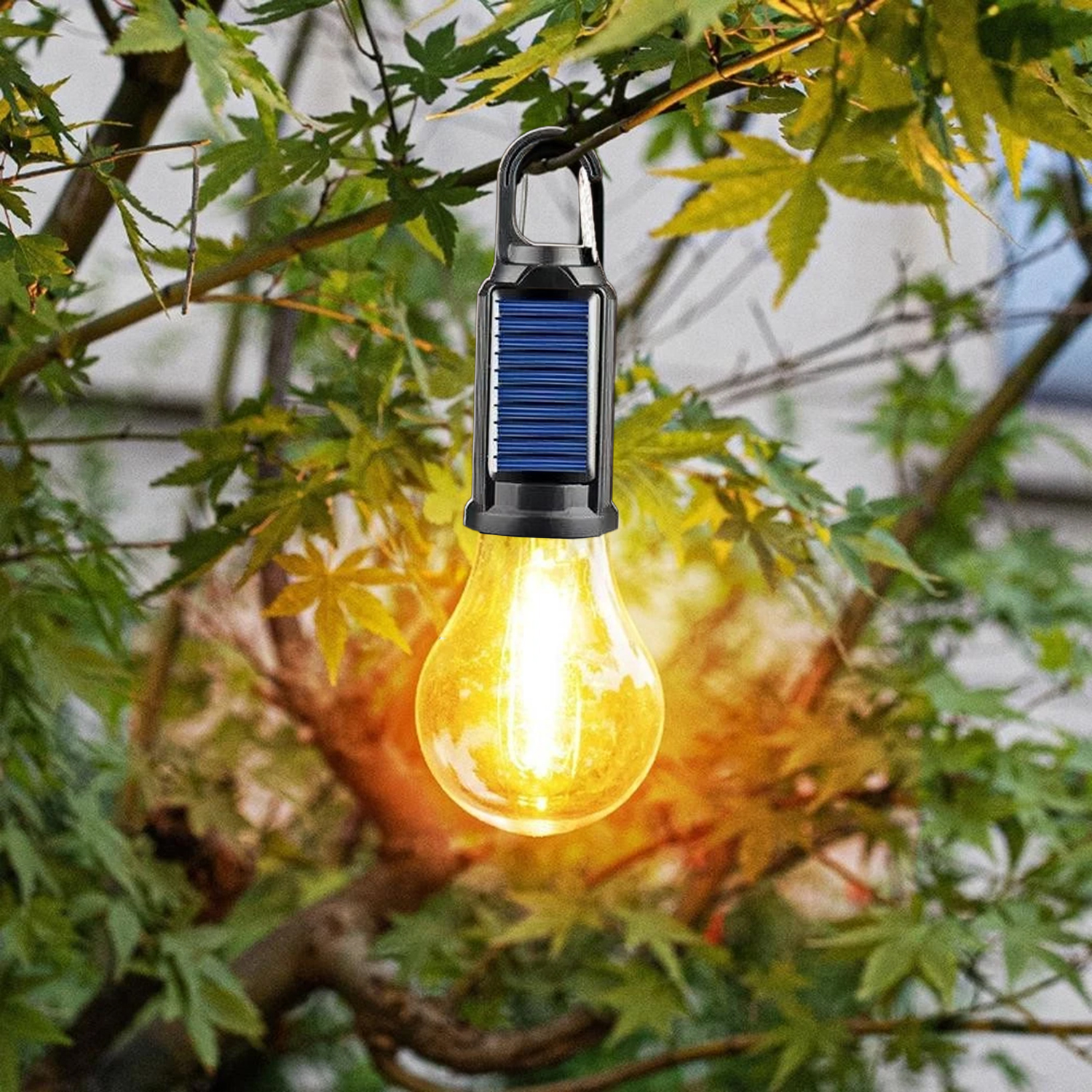 Una lampada solare a forma di lampadina incandescente è appesa a un ramo. Le foglie verdi la circondano, con la luce che illumina la scena.