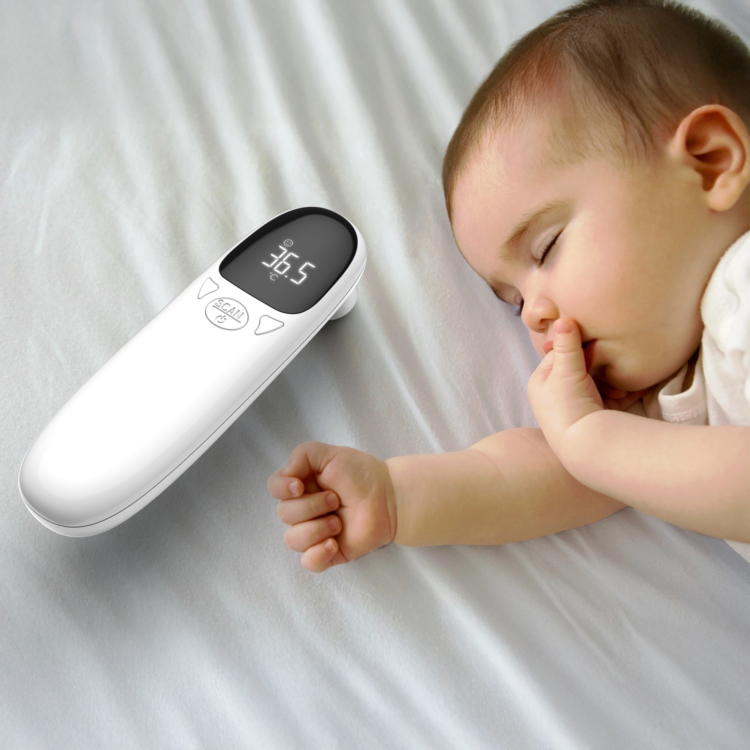 Ein Baby schläft neben einem weißen Thermometer mit 36,5 Grad. Das Baby hat den Finger im Mund und liegt auf weißer Bettwäsche.