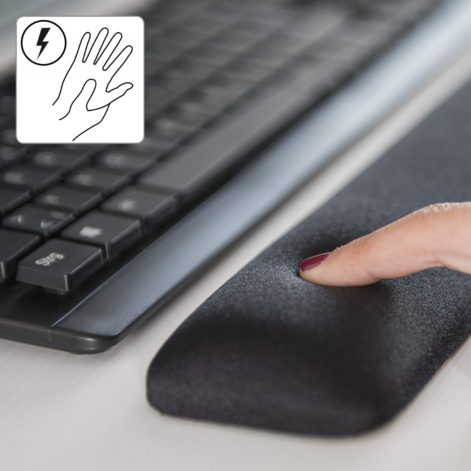 Eine Hand drückt einen Finger in eine schwarze Handgelenkauflage neben einer Tastatur. Ein Handsymbol mit einem Blitz befindet sich in der Ecke.