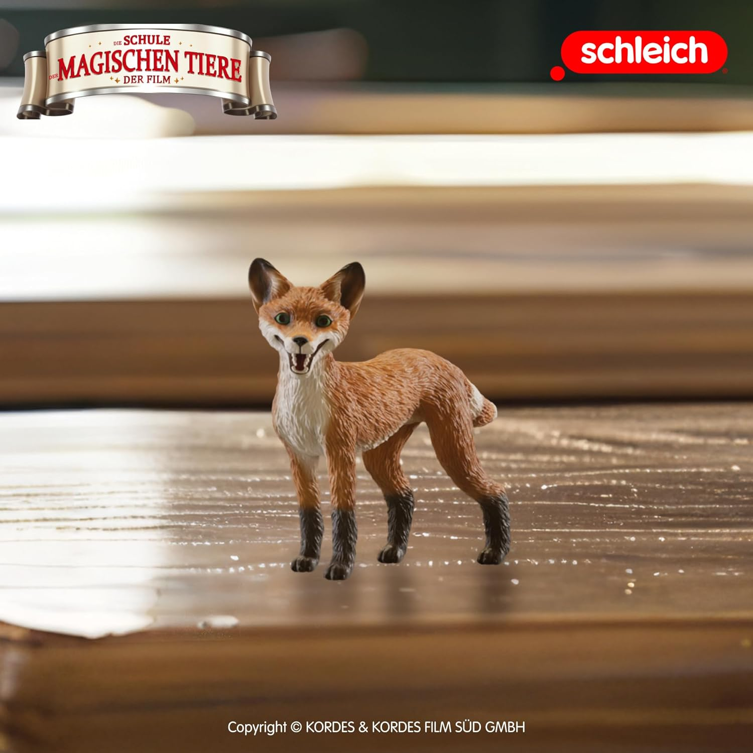 Zabawkowa lis z brązowym i białym futrem stoi na drewnianej powierzchni. U góry widnieje baner z niemieckim tekstem. Widoczne jest również logo Schleich.