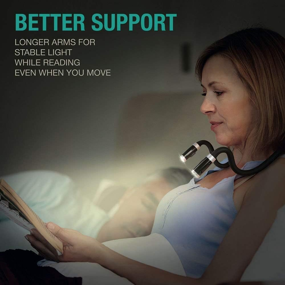 Eine Frau liest nachts ein Buch. Sie trägt eine Nackenleuchte mit zwei Lampen. Im Hintergrund ist eine verschwommene Person im Bett zu sehen.