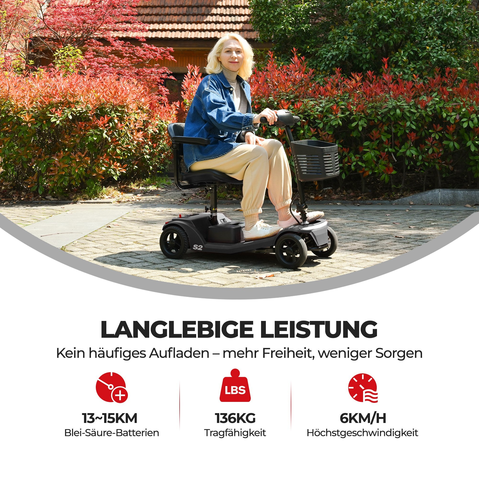 Kobieta na czarnym skuterze inwalidzkim na utwardzonej ścieżce. Czerwone i zielone krzewy w tle.