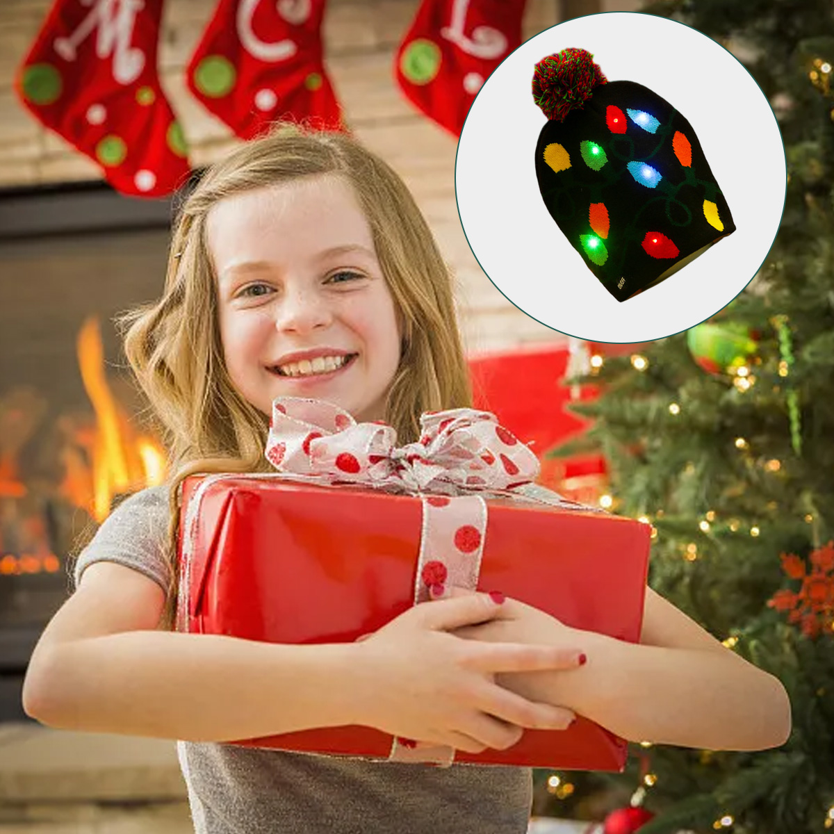 Ein lächelndes Mädchen hält ein rot verpacktes Geschenk. Weihnachtsstrümpfe und ein Baum im Hintergrund. Eine Mütze mit Lichtern ist in einem Kreis.