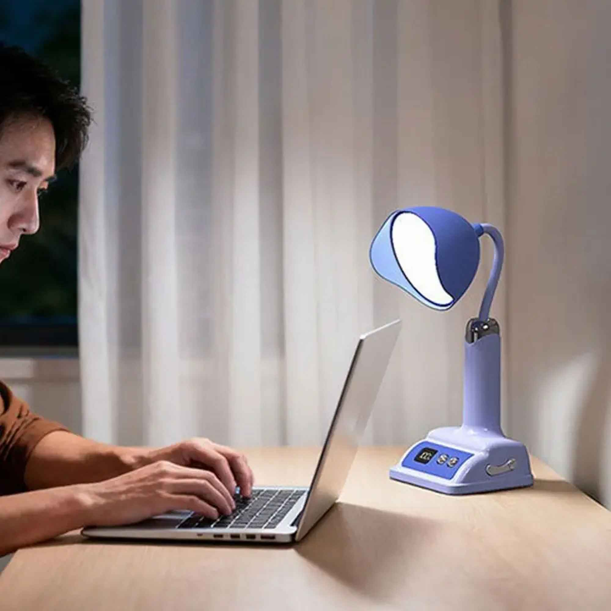 Ein Mann benutzt einen Laptop unter einer blauen Lampe. Die Szene ist drinnen mit einem Fenster und weißen Vorhängen.