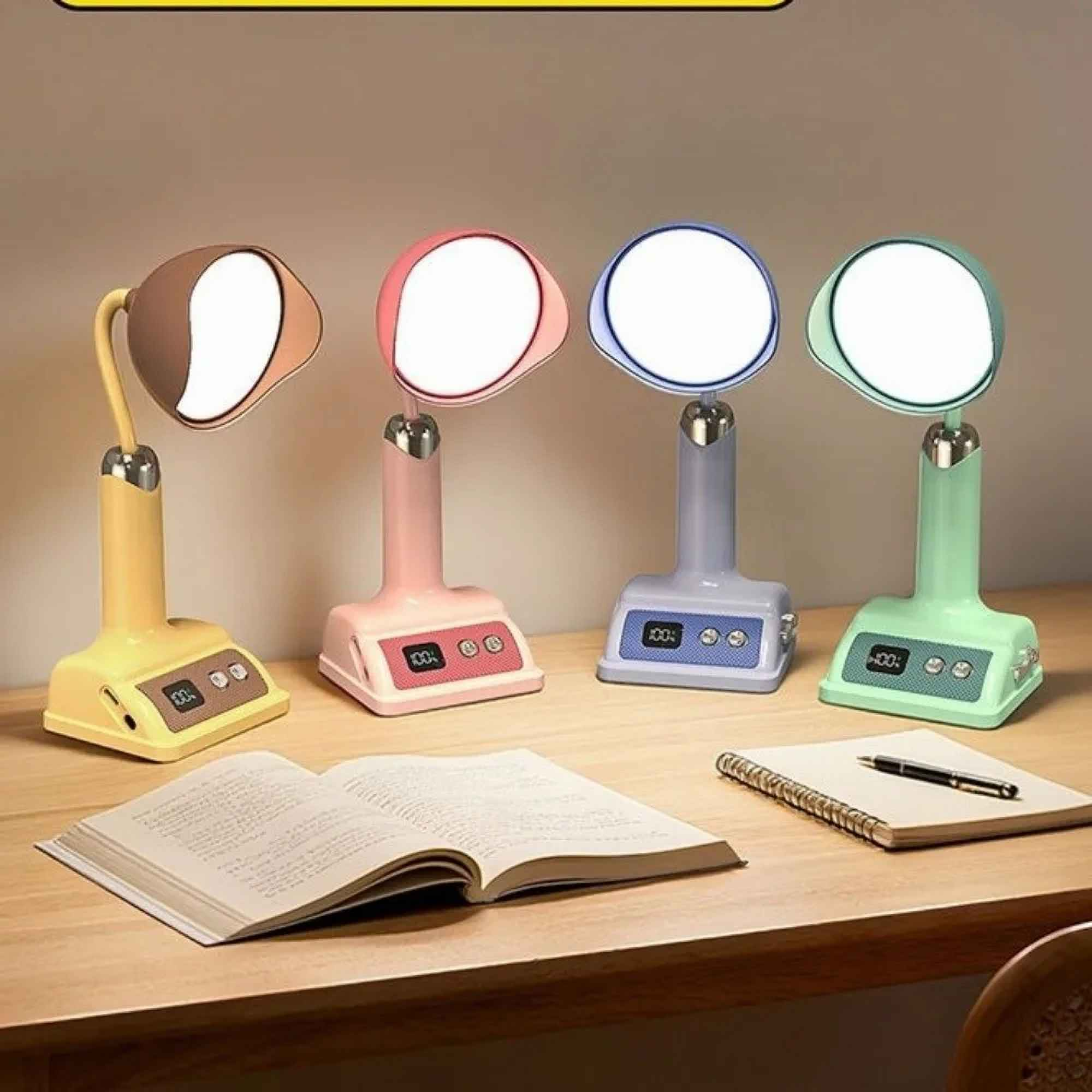 Vier bunte Schreibtischlampen mit offenen Büchern und einem Notizblock auf einem Holztisch. Jede Lampe hat ein rundes Licht.
