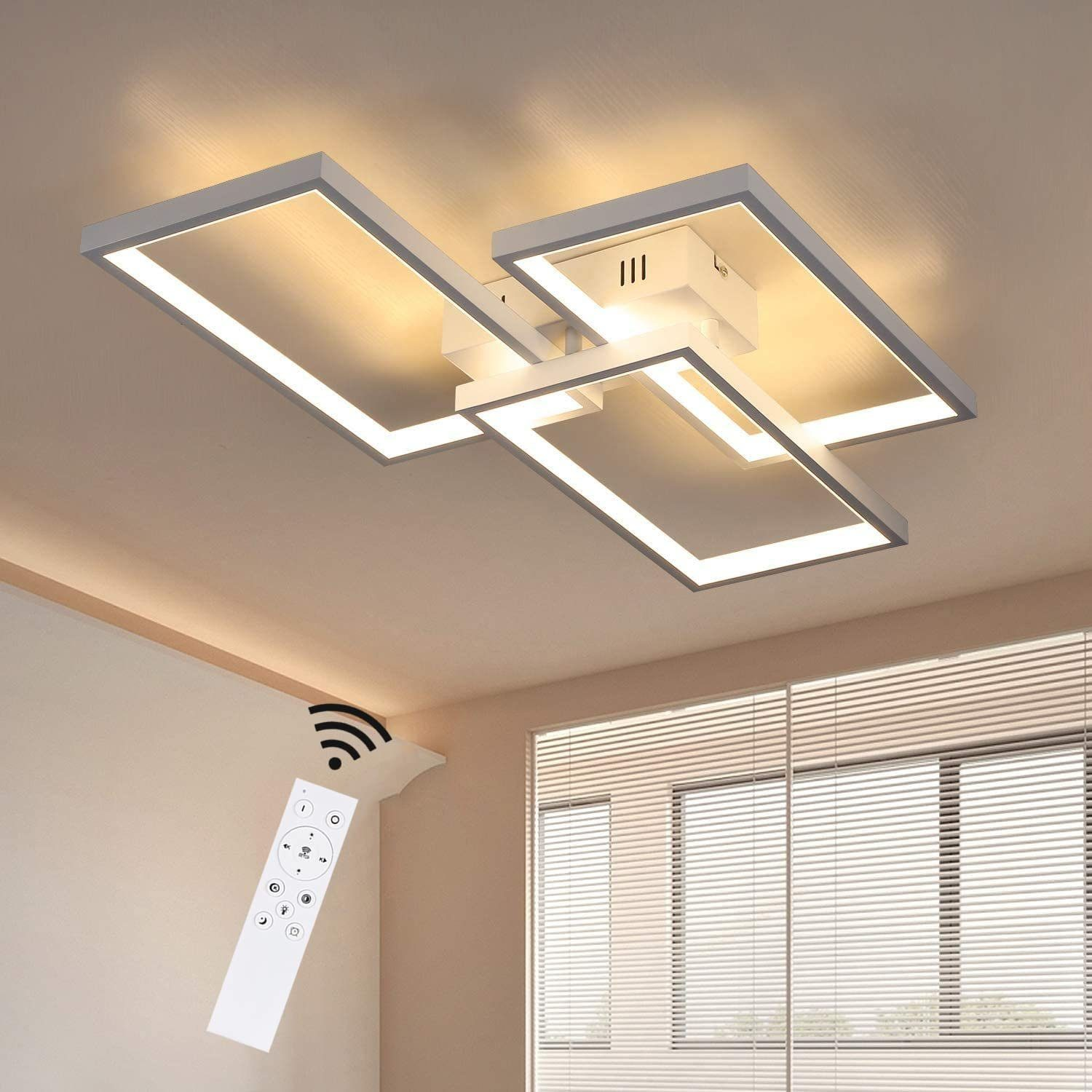 Una moderna plafoniera con telecomando. La luce ha un design quadrato. Un telecomando è in primo piano e le tende sullo sfondo.