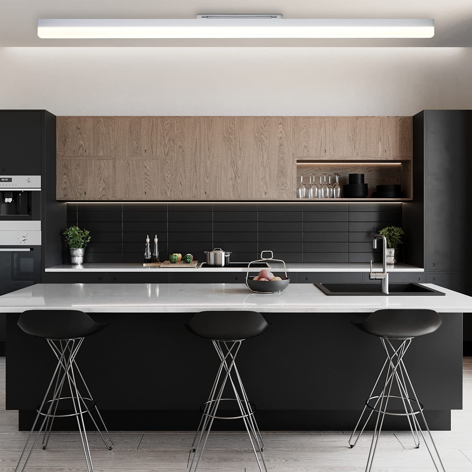 Cucina moderna con mobili neri, pensili in legno e un'isola con piano di lavoro bianco con tre sgabelli neri.