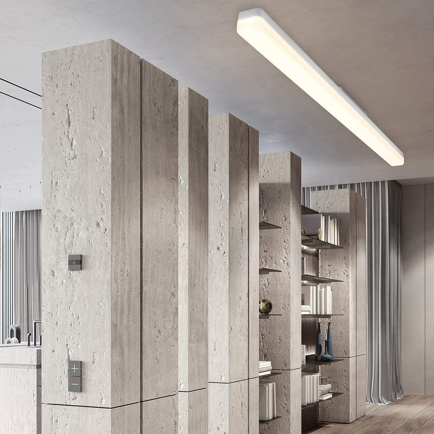Scatto interno con pilastri in pietra, scaffali con libri e una lunga luce a soffitto. Pavimento in legno e tenda sullo sfondo.