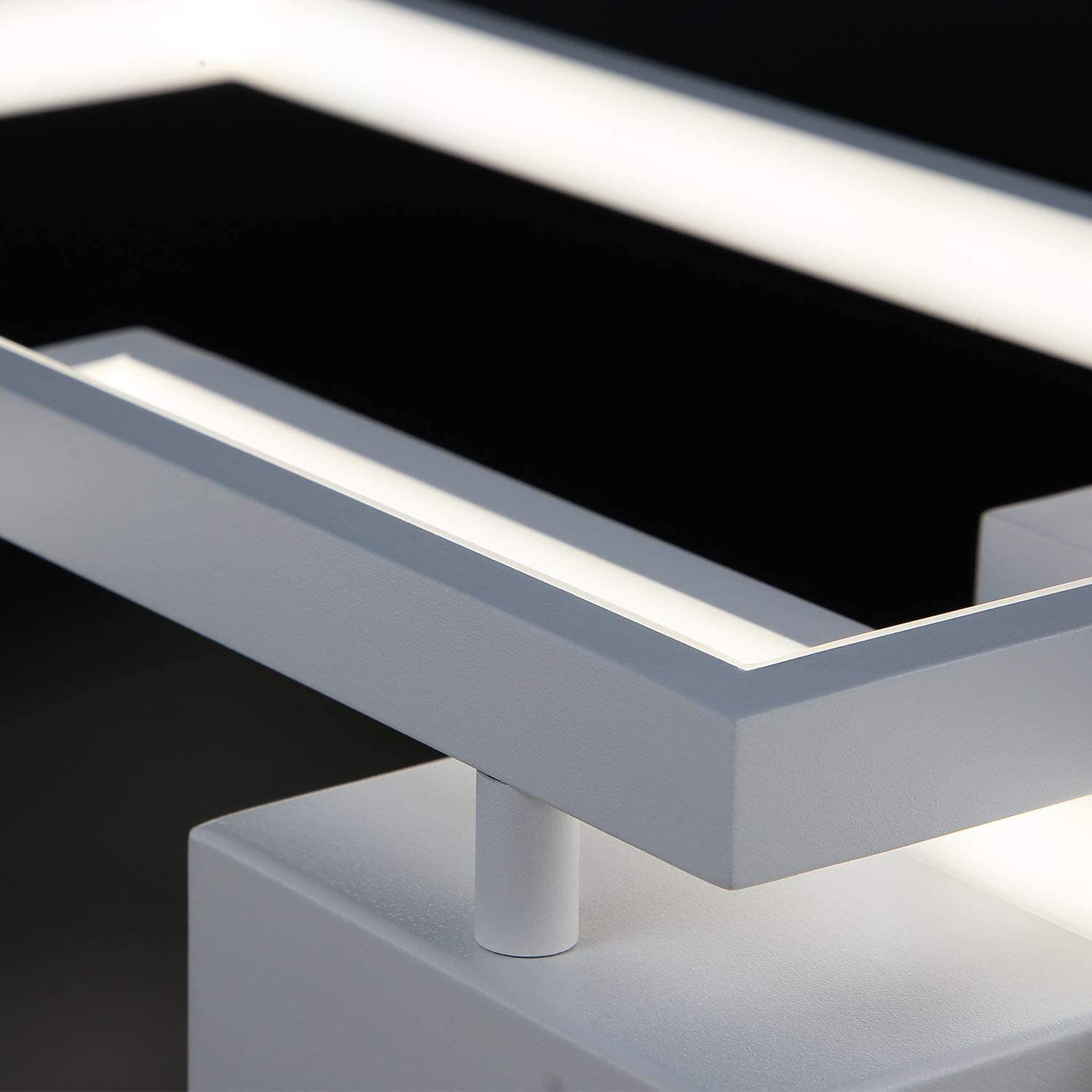 Primo piano di un moderno apparecchio di illuminazione bianco. Presenta un design geometrico con forme quadrate e rettangolari, illuminato all'interno.