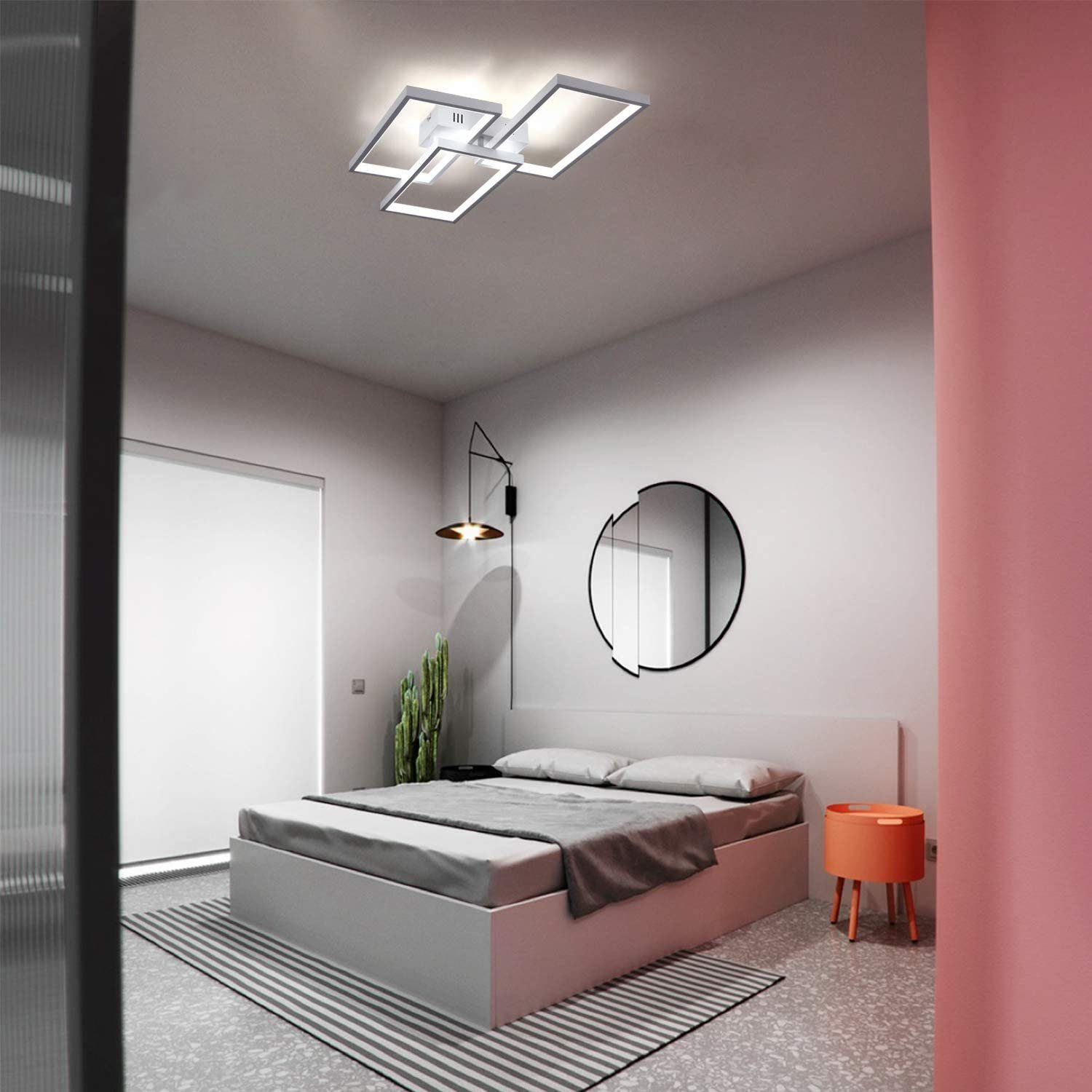 Camera da letto con letto, tappeto, specchio e lampada moderna. Colori: grigio, bianco e corallo. Visibile anche un cactus.