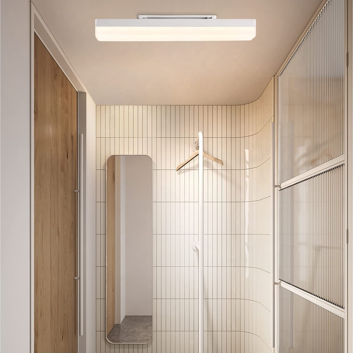 Wnętrze korytarza. Jest drewniane drzwi, lustro i wieszak. Ściany są kafelkowane. Długie oświetlenie znajduje się na suficie.