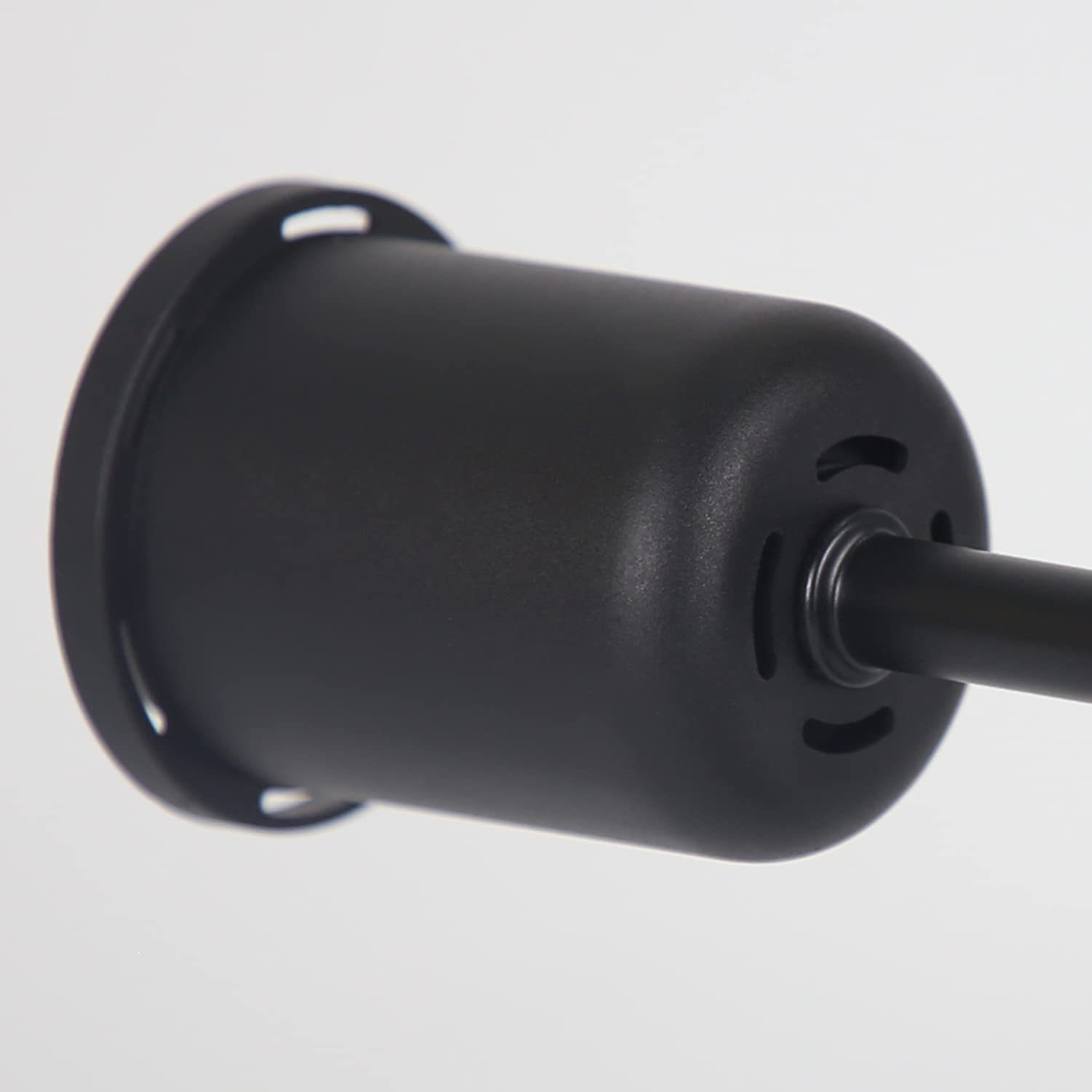 Primer plano de una lámpara negra. Tiene un cuerpo cilíndrico con una base circular y una varilla que se extiende desde ella.