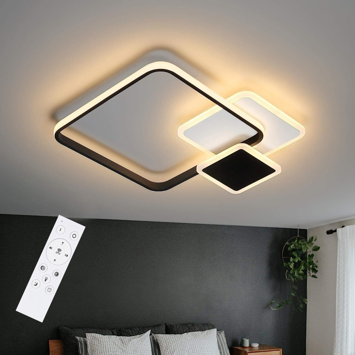 Geometrische Deckenleuchte mit Fernbedienung. Schwarze und weiße Quadrate. Schlafzimmer mit grauer Wand, Bett und Pflanze.