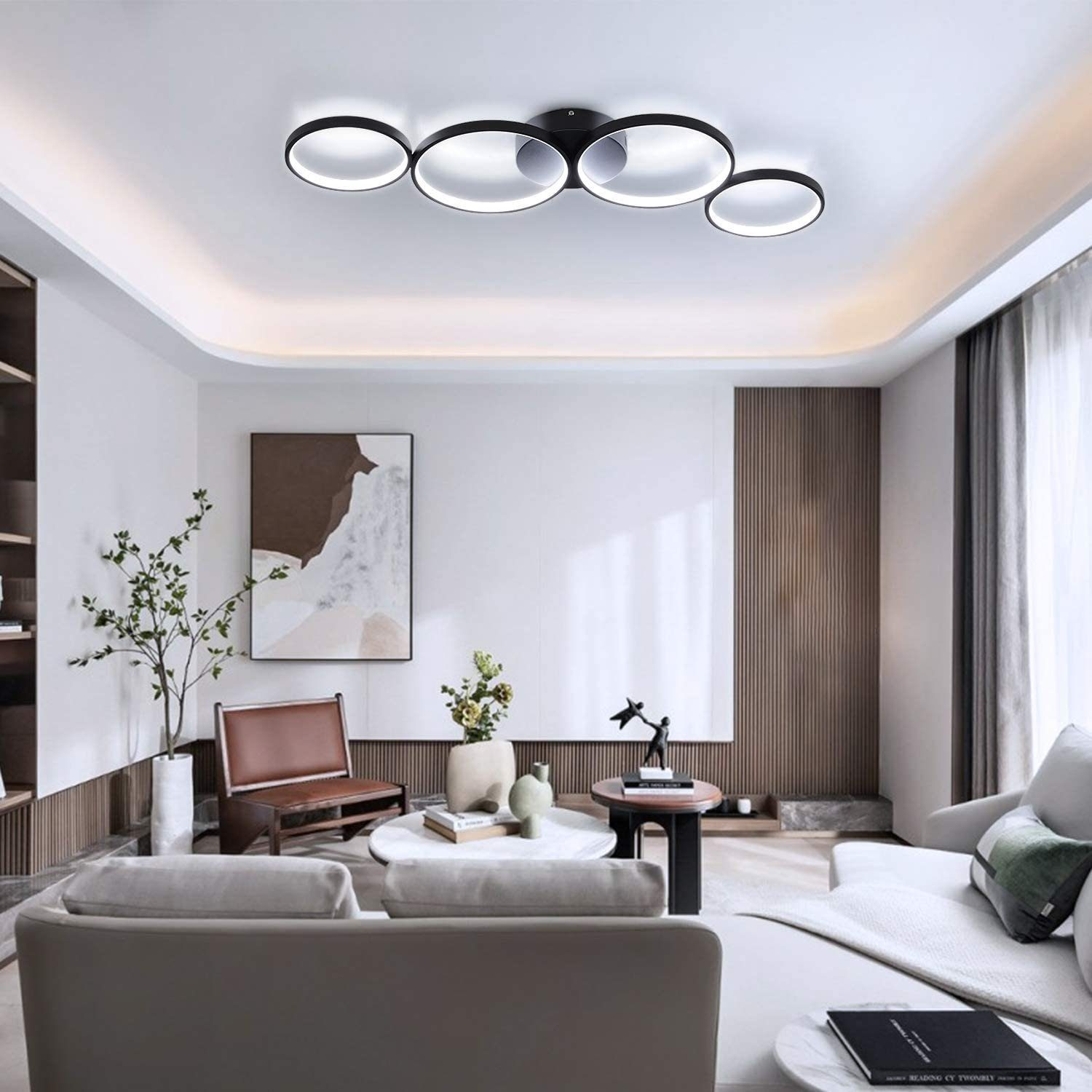 Soggiorno con moderne luci a soffitto. Caratteristiche includono un divano, sedie, opere d'arte, piante e un tavolino, tutto in toni neutri.