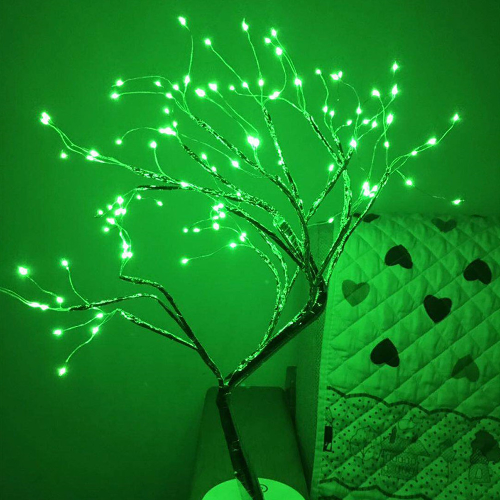Ein dekorativer Baum mit grünen Lichtern. Der Baum steht vor einer grünen Tagesdecke mit Herzmustern. Der Hintergrund ist ebenfalls grün.
