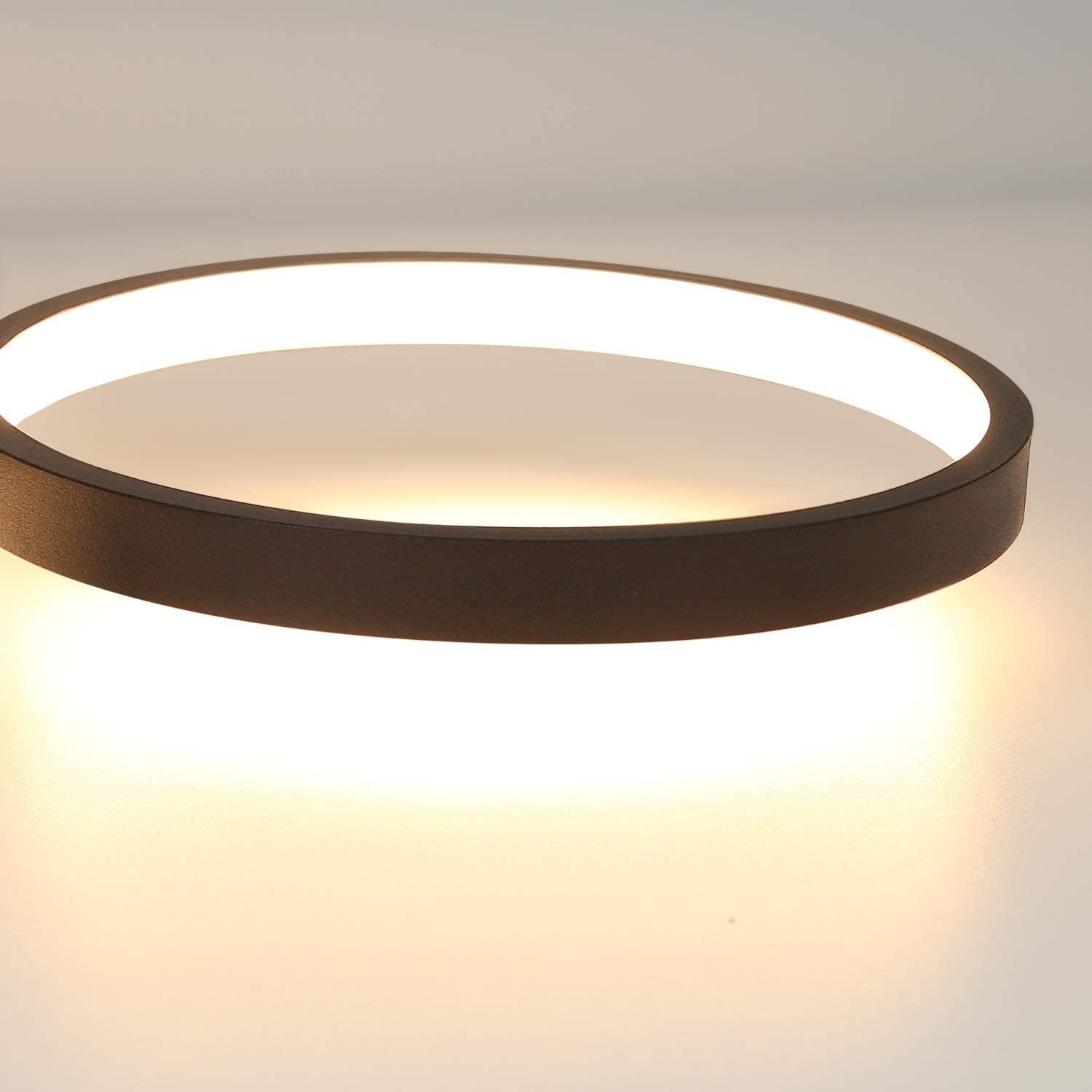 Primo piano di un moderno apparecchio di illuminazione a soffitto circolare. La luce è bianca brillante, con un anello esterno marrone scuro.