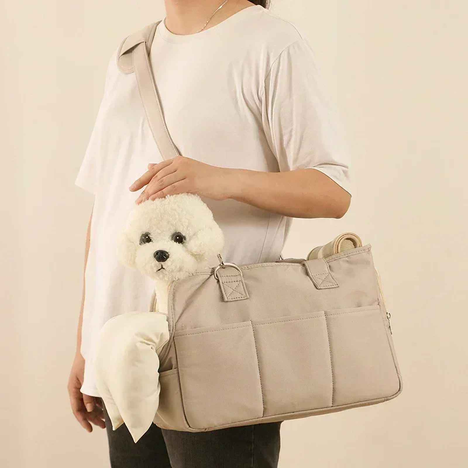 Eine Person trägt eine beige Hundetasche, aus der ein Plüschhund herausschaut. Die Person trägt ein weißes Hemd.