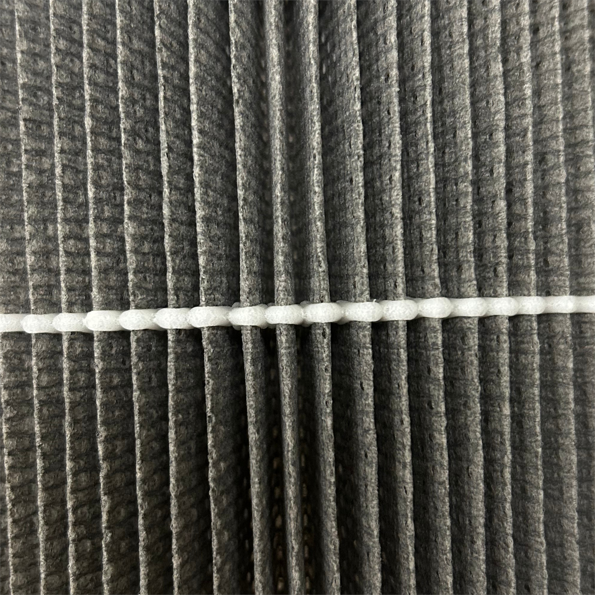 Nahaufnahme eines Filters. Er hat vertikale graue, plissierte Abschnitte mit einem weißen horizontalen Streifen.