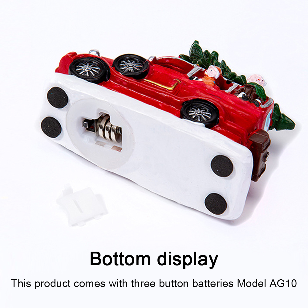 Ein rotes Spielzeugauto mit Weihnachtsbaum. Das Auto steht auf weißer Basis mit schwarzen Kreisen. Der Boden zeigt das Batteriefach.