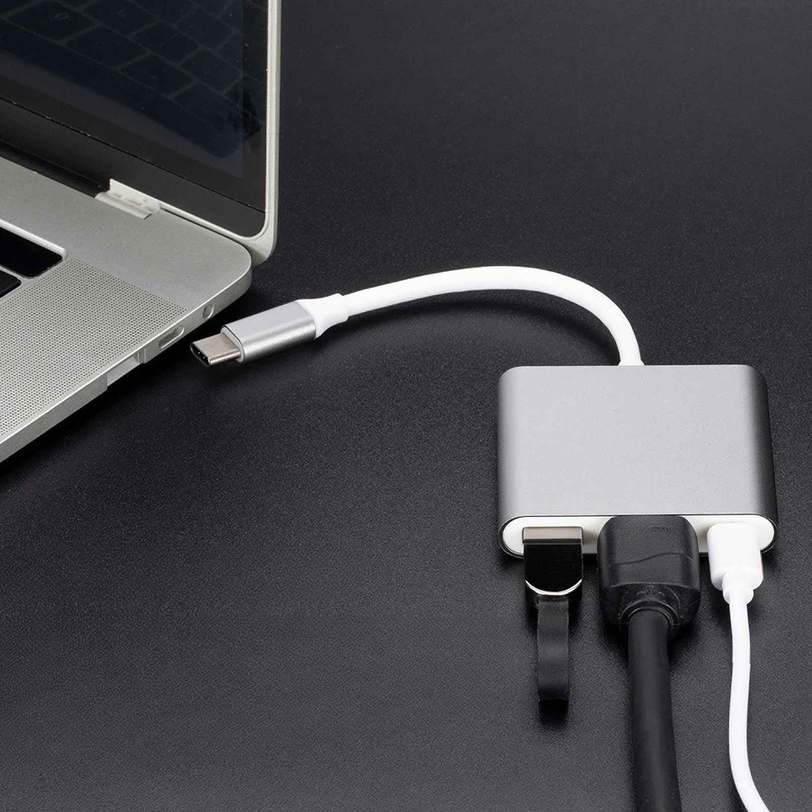 Ein Laptop ist mit einem silbernen USB-Hub mit schwarzen und weißen Kabeln auf einer schwarzen Oberfläche verbunden.