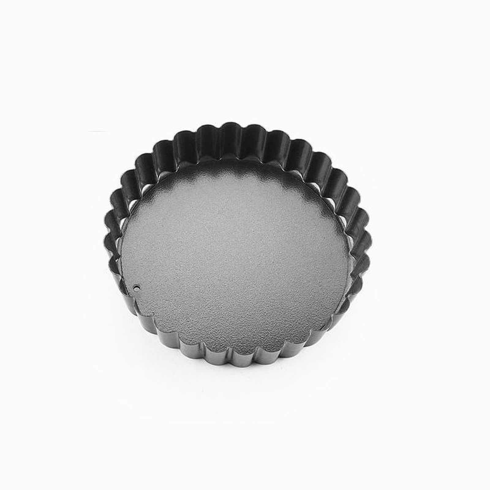 Eine runde, geriffelte, dunkle Metall-Tarteform liegt auf weißem Hintergrund.