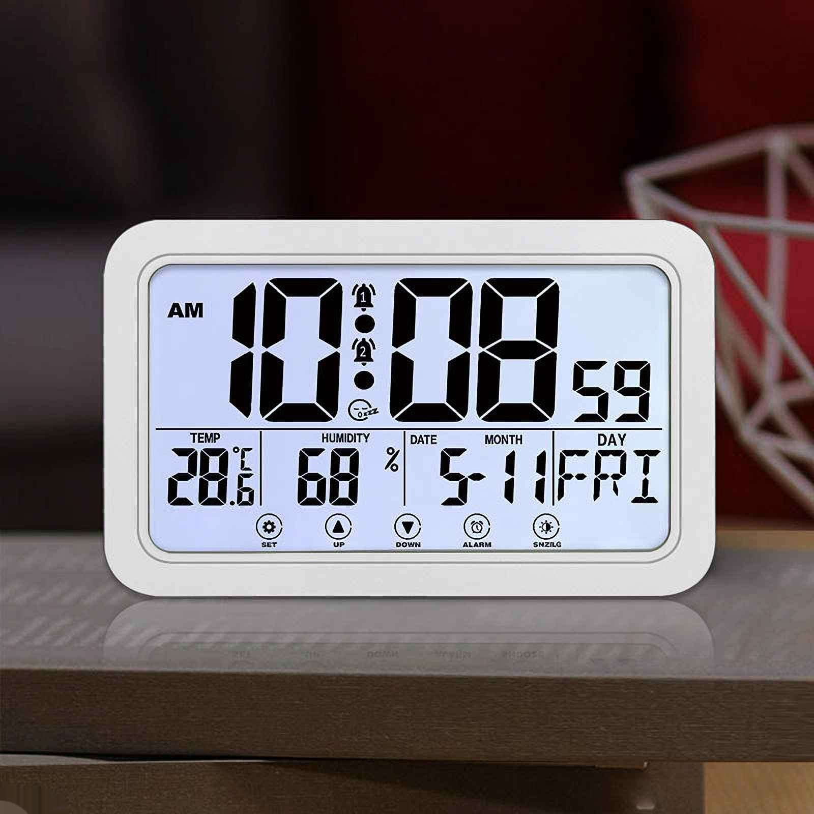 Eine weiße Digitaluhr zeigt Zeit, Datum, Luftfeuchtigkeit und Temperatur auf einem blau beleuchteten Bildschirm an, der auf Holz steht.