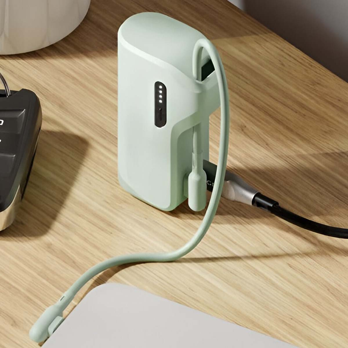 Eine mintgrüne Powerbank ist mit einem Ladekabel verbunden. Die Powerbank befindet sich auf einer Holzoberfläche.