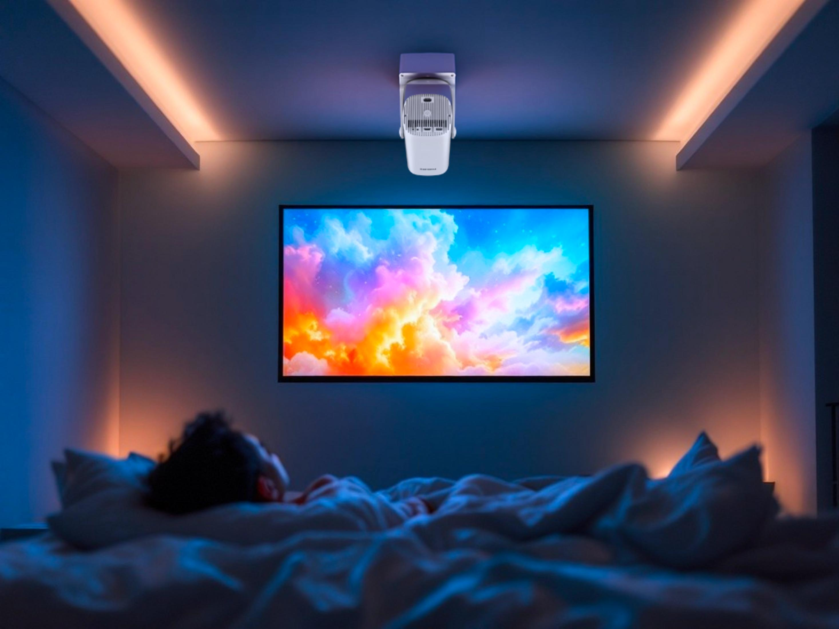 Eine Person schläft im Bett. Ein Fernseher zeigt einen farbenfrohen Himmel. Ein Projektor hängt an der Decke. Der Raum hat orangefarbene und blaue Lichter.