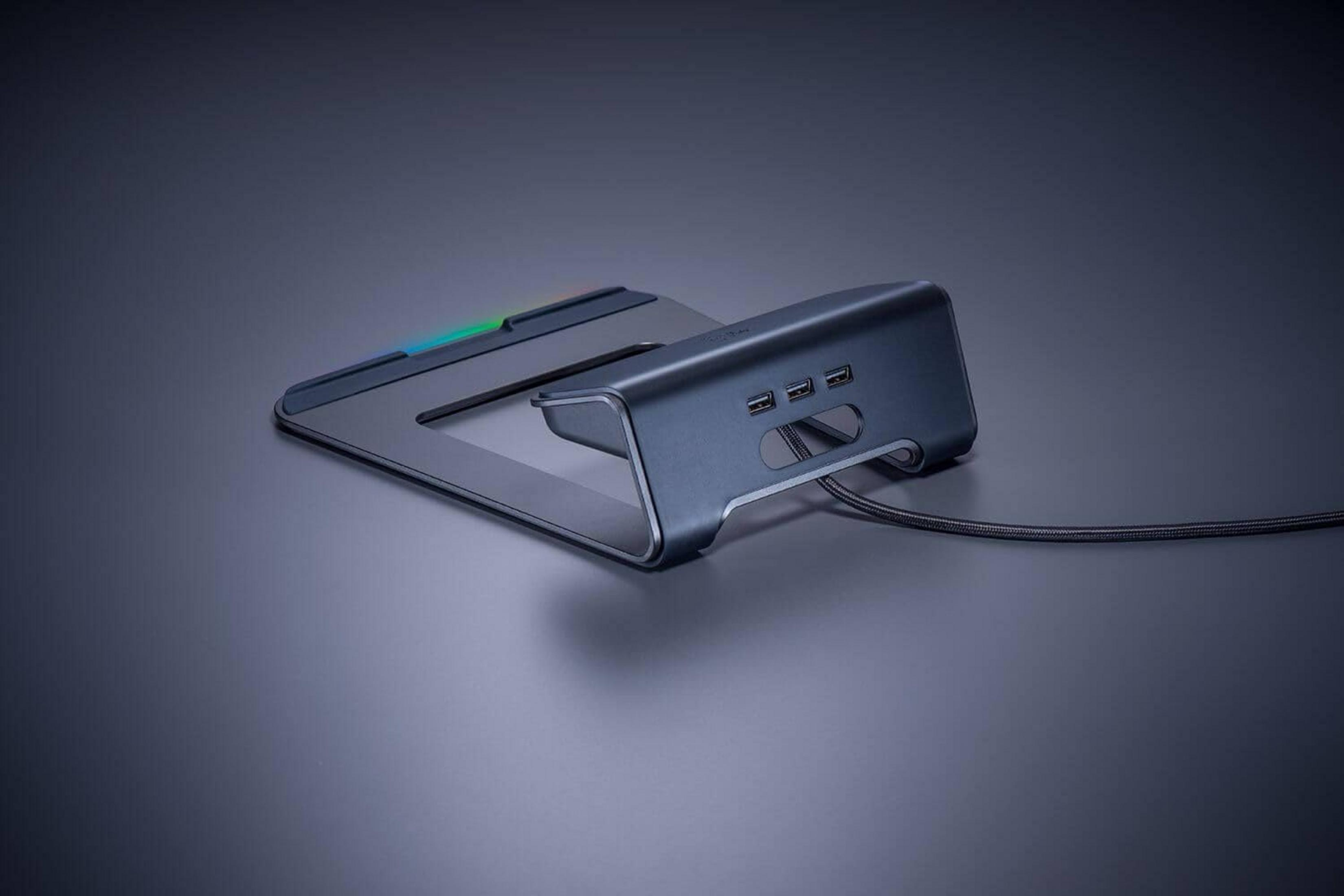 Ciemnoszara podstawka pod laptopa z portami USB i kablem na ciemnej powierzchni.